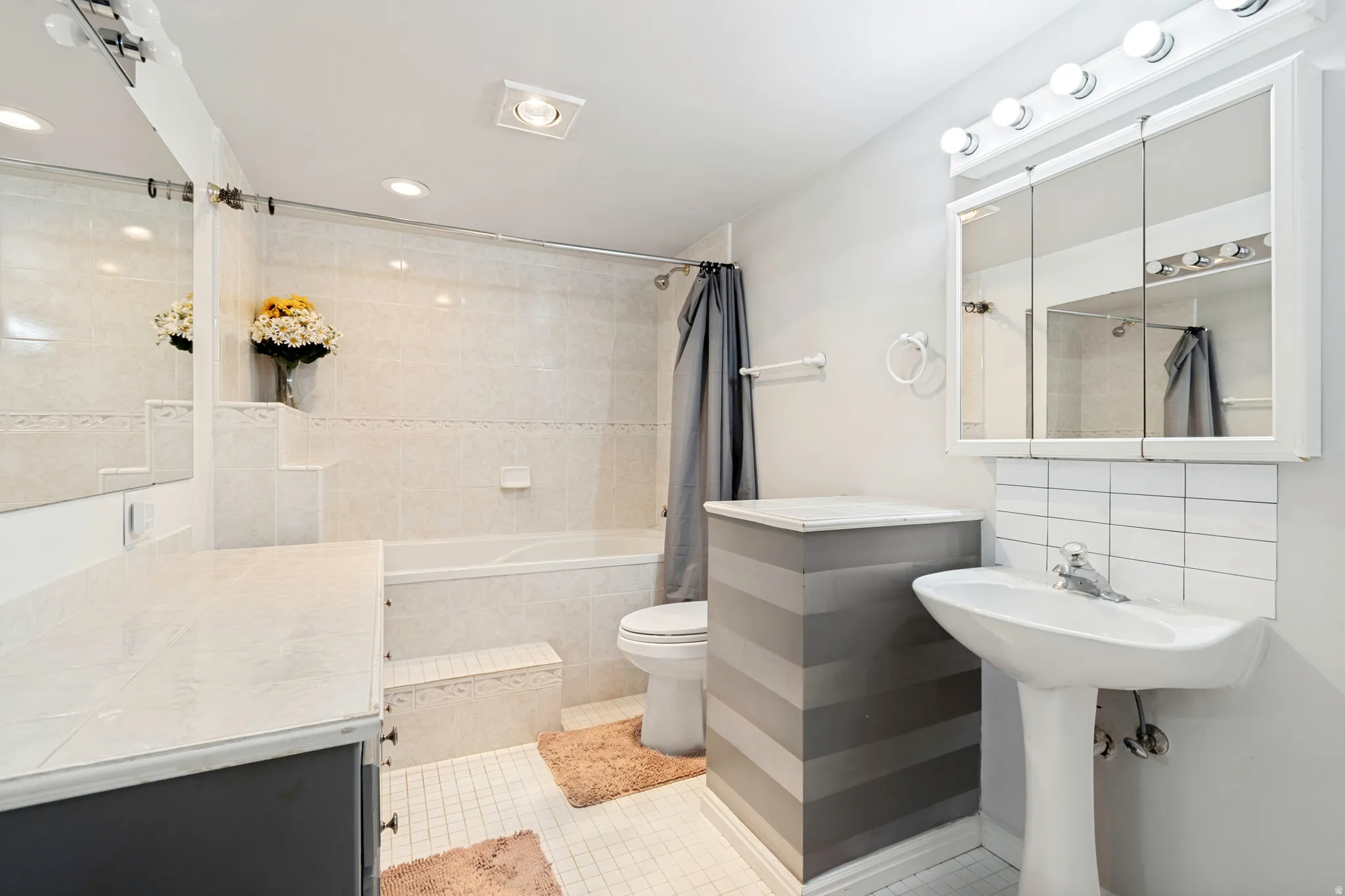 Bathroom featuring a tiled tub surround, recessed lighting, and a pedestal sink