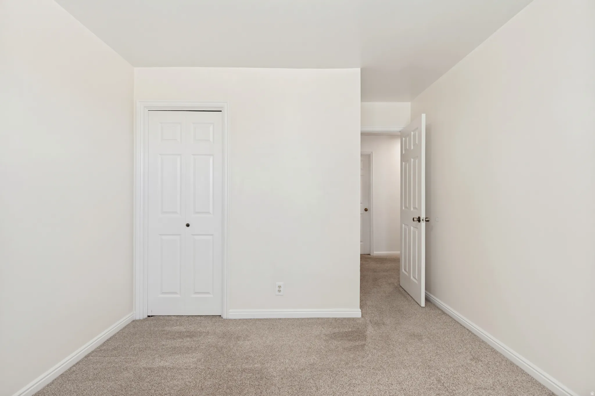 Neutral-toned interior room featuring light beige walls and complementing carpet flooring