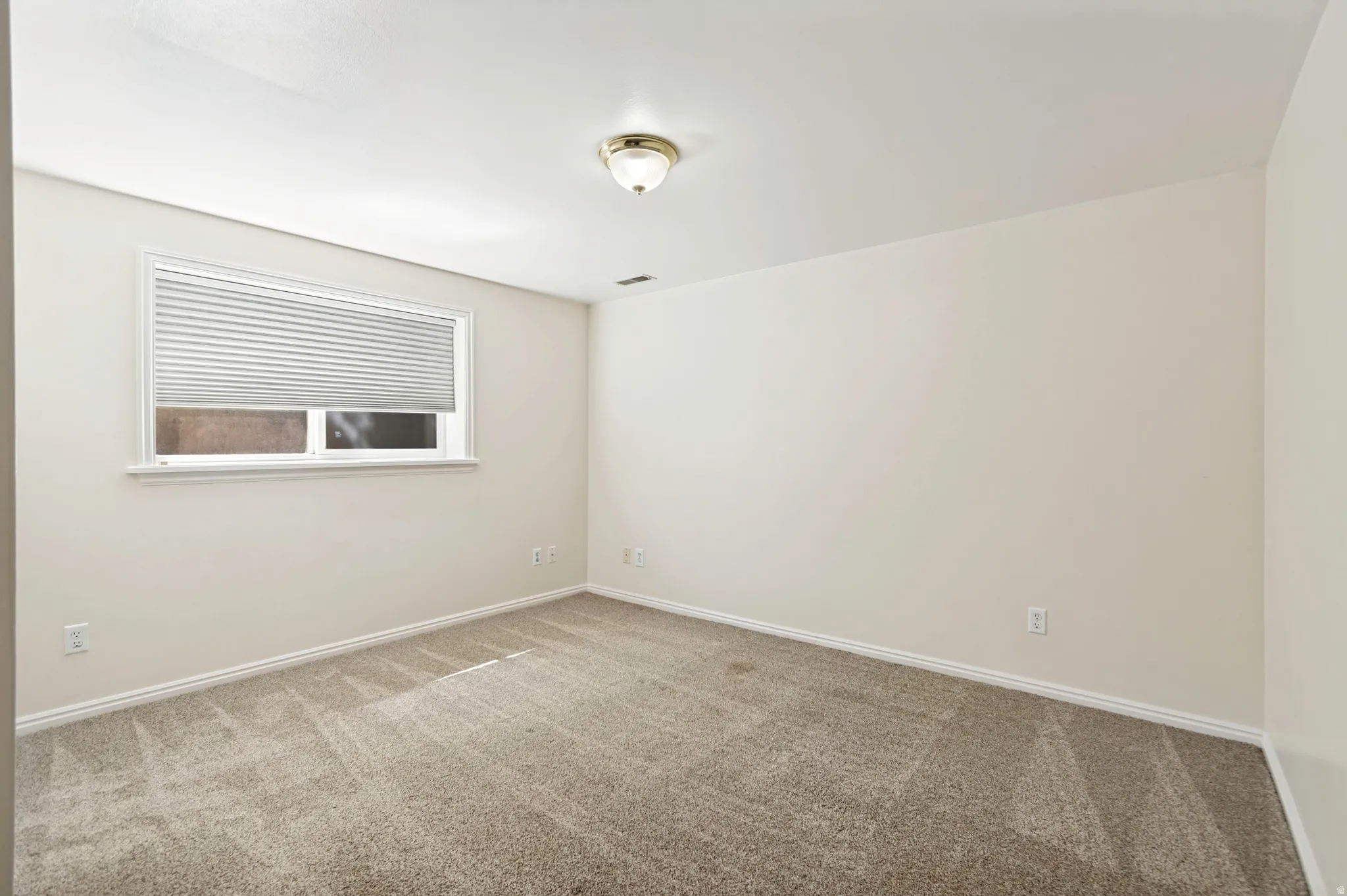 Windowed interior space with light-toned walls and neutral carpeting