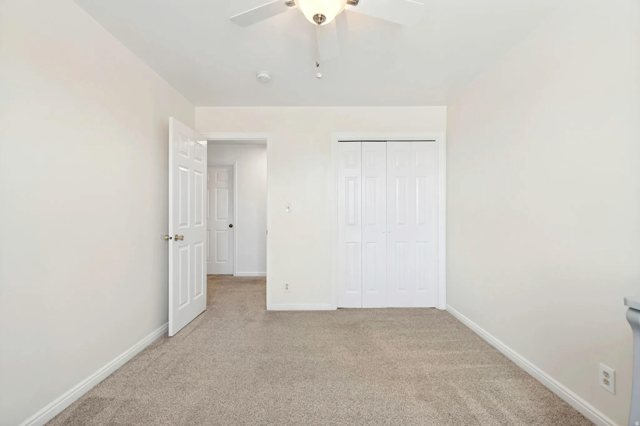 Neutral-toned room featuring light beige carpeting and white walls
