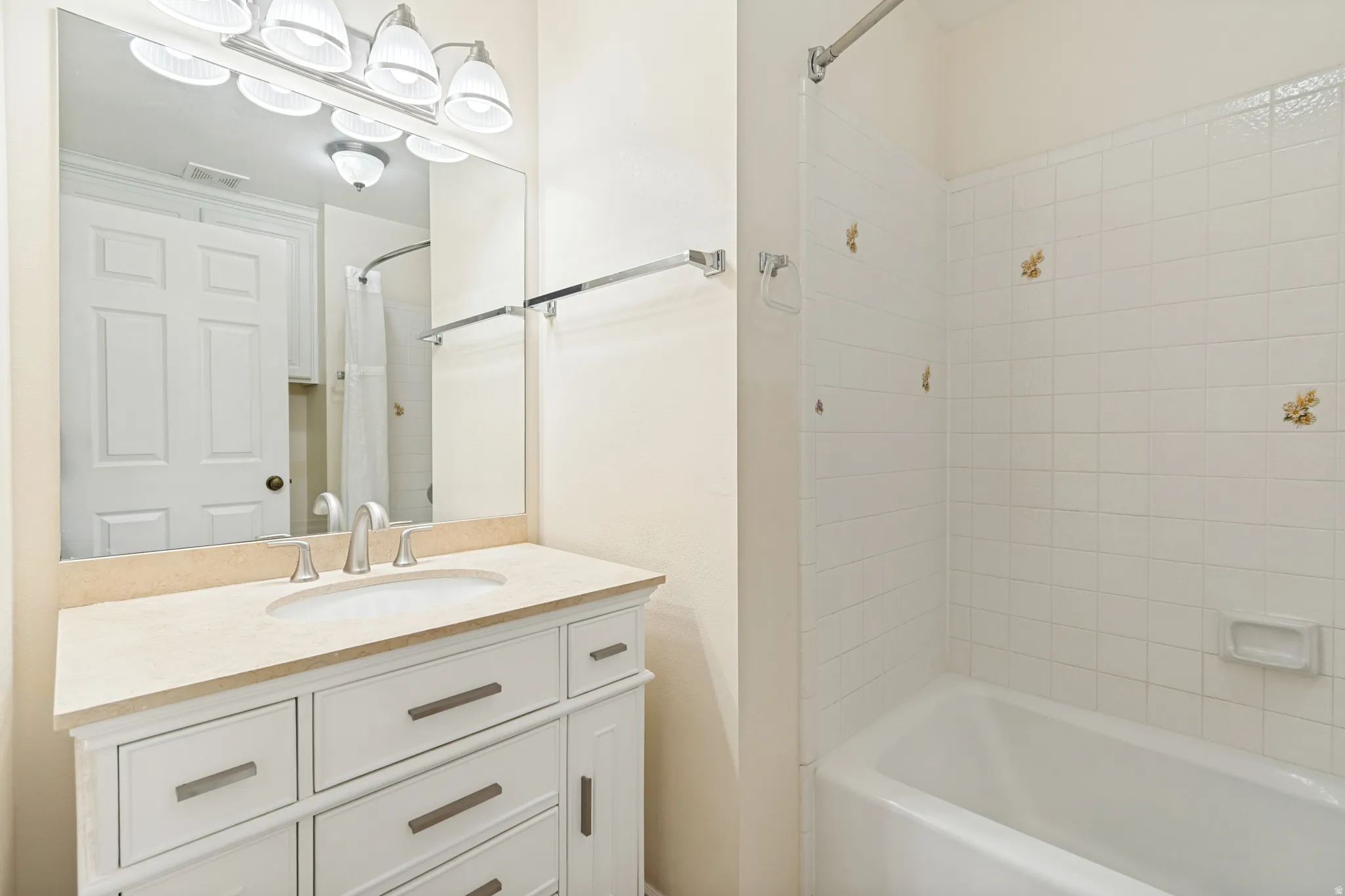 Bathroom featuring a vanity with a light-toned countertop, an undermount sink, and a chrome faucet