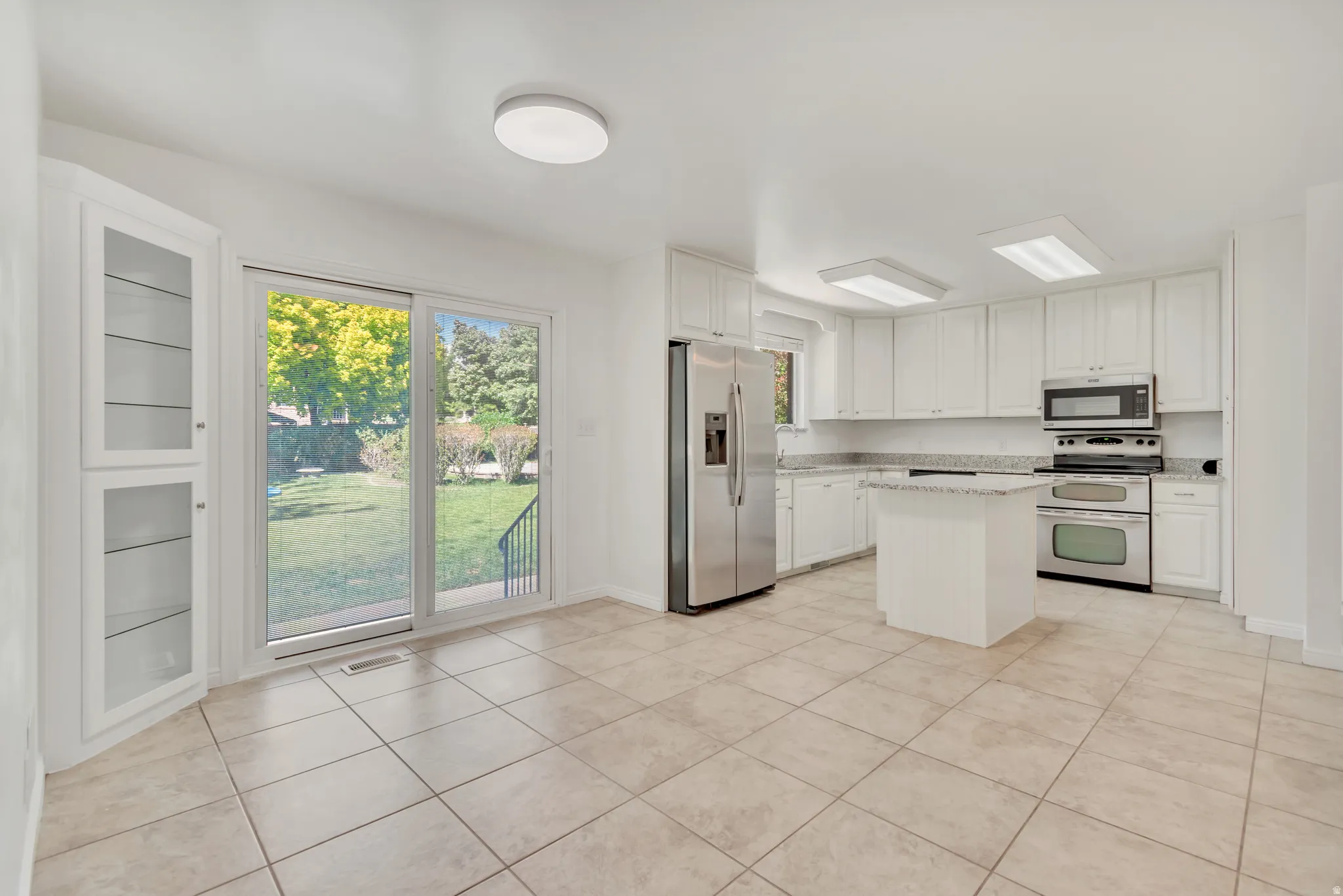 Spacious kitchen with white cabinetry, stainless steel appliances, and a central island