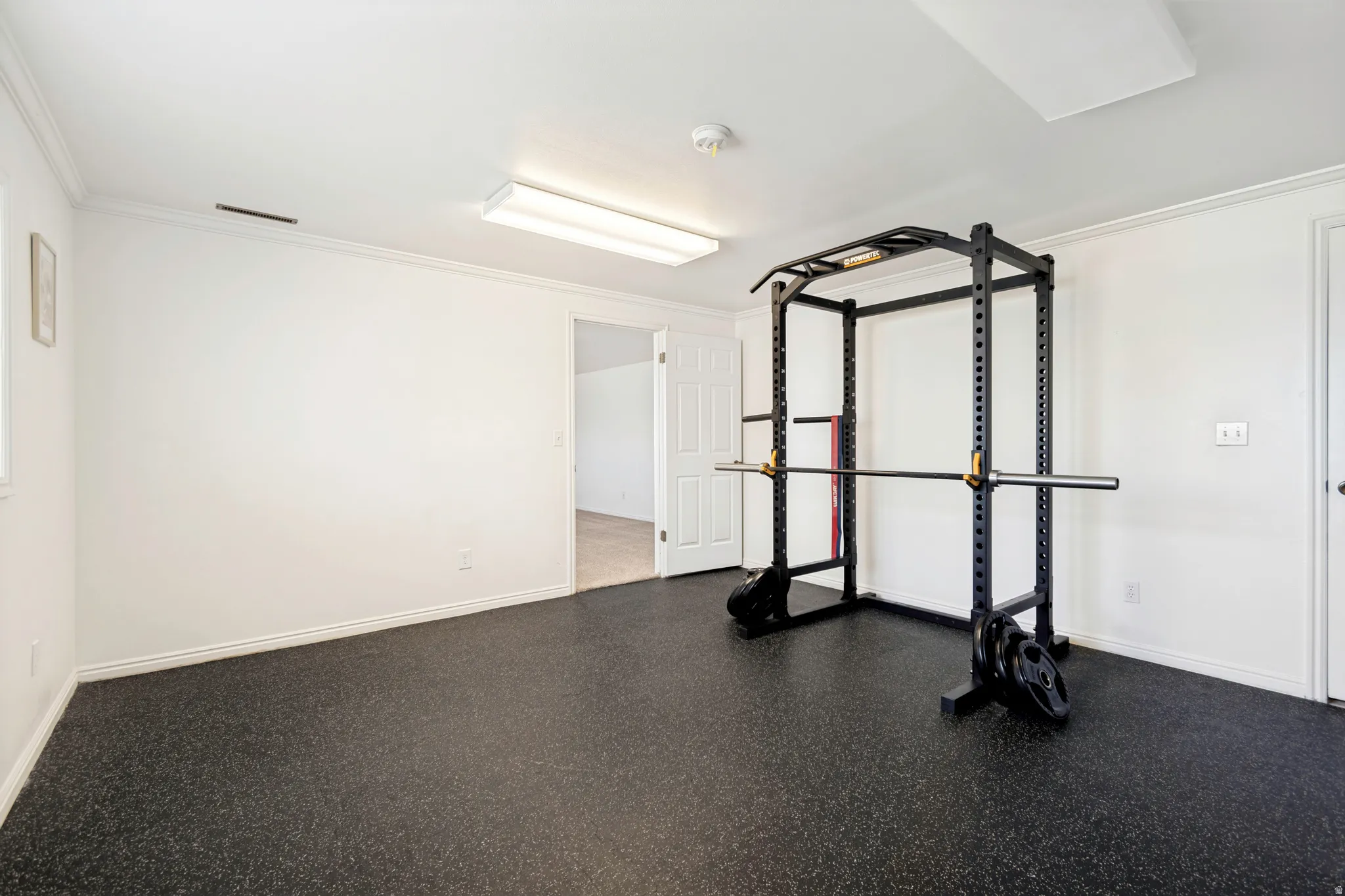 Dedicated fitness room featuring durable rubber flooring, white walls, and bright overhead lighting