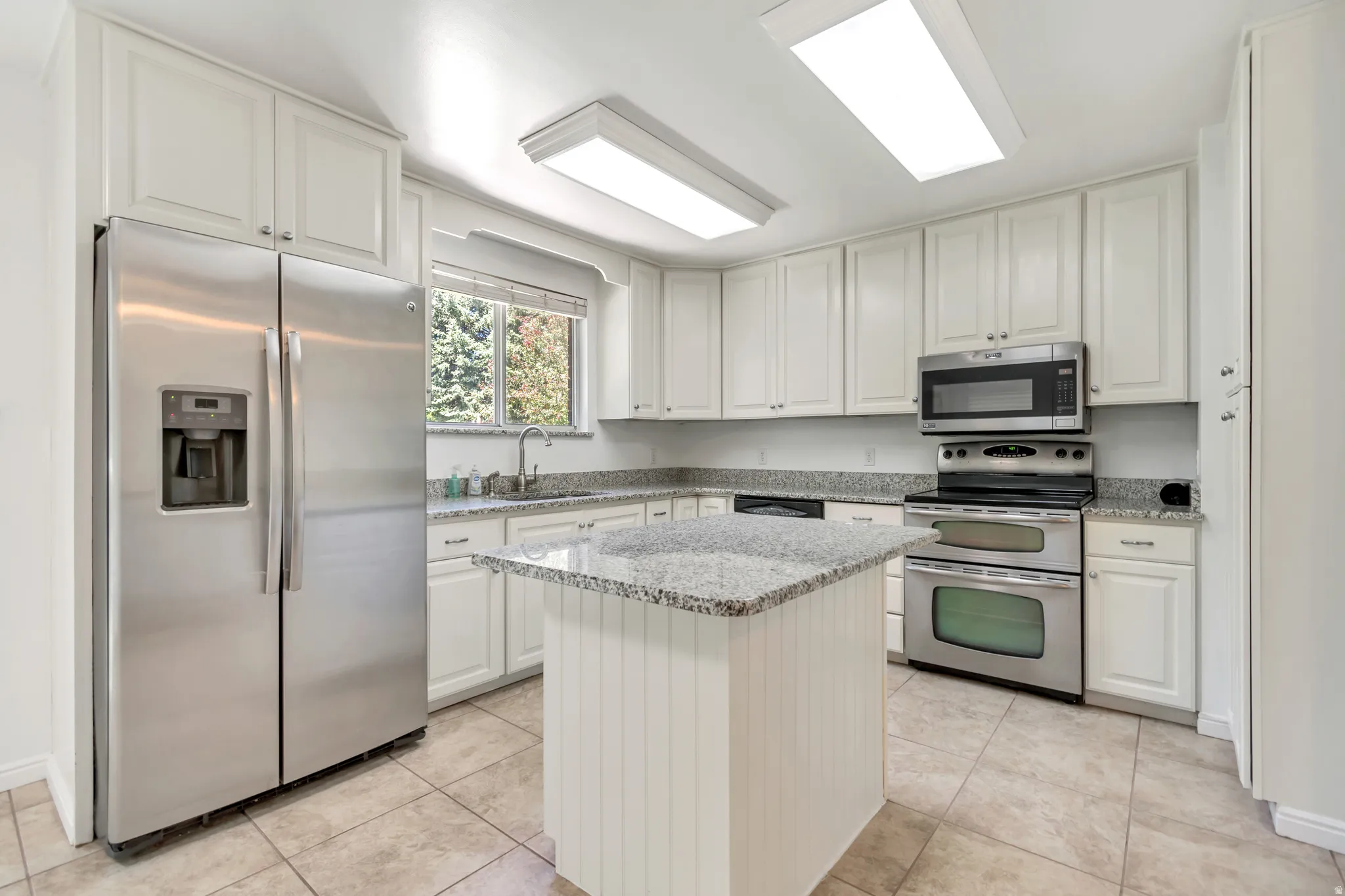 Kitchen featuring light-toned cabinetry, granite countertops, and stainless steel appliances