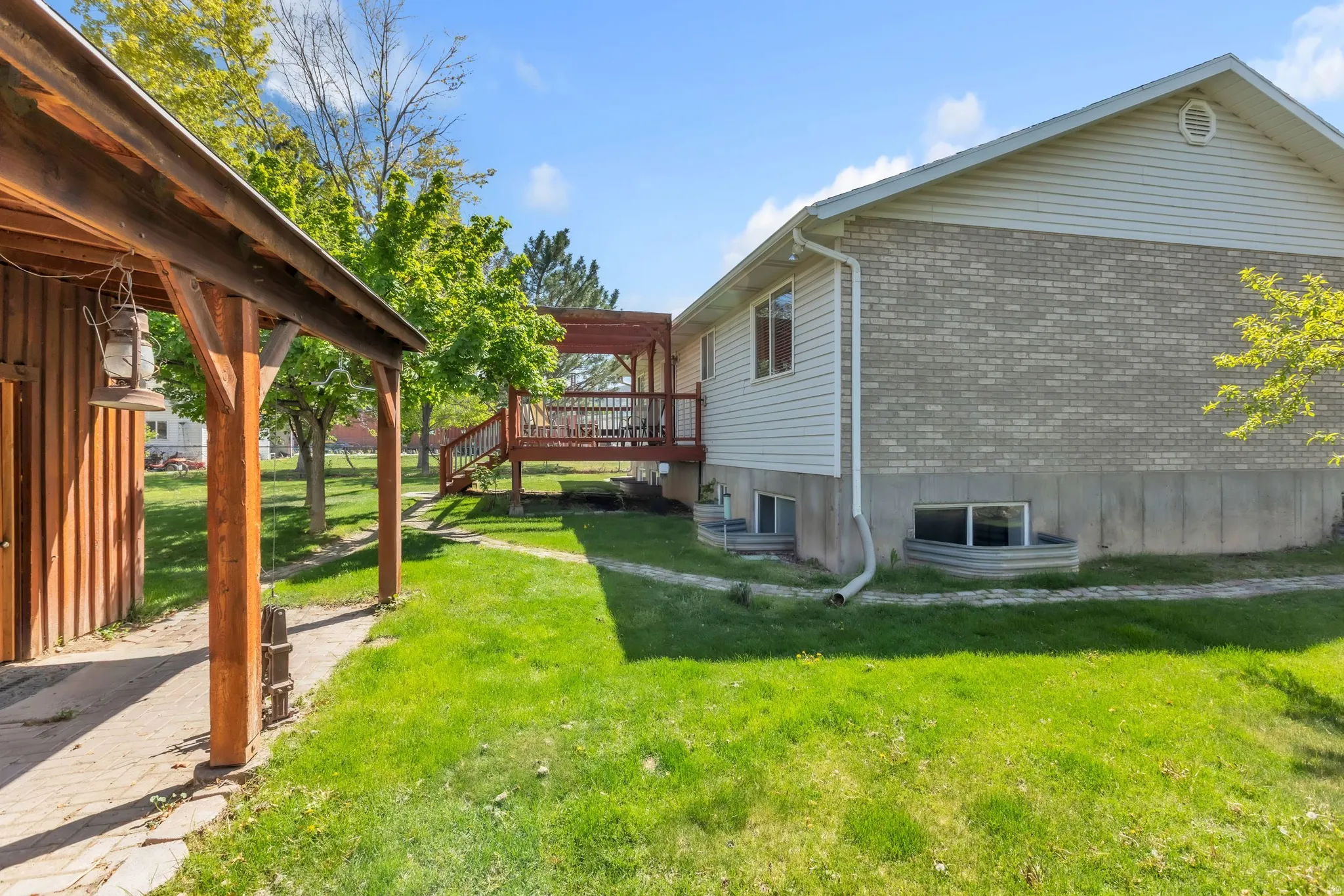 View of home's exterior with a wooden deck, a lawn, and brick siding