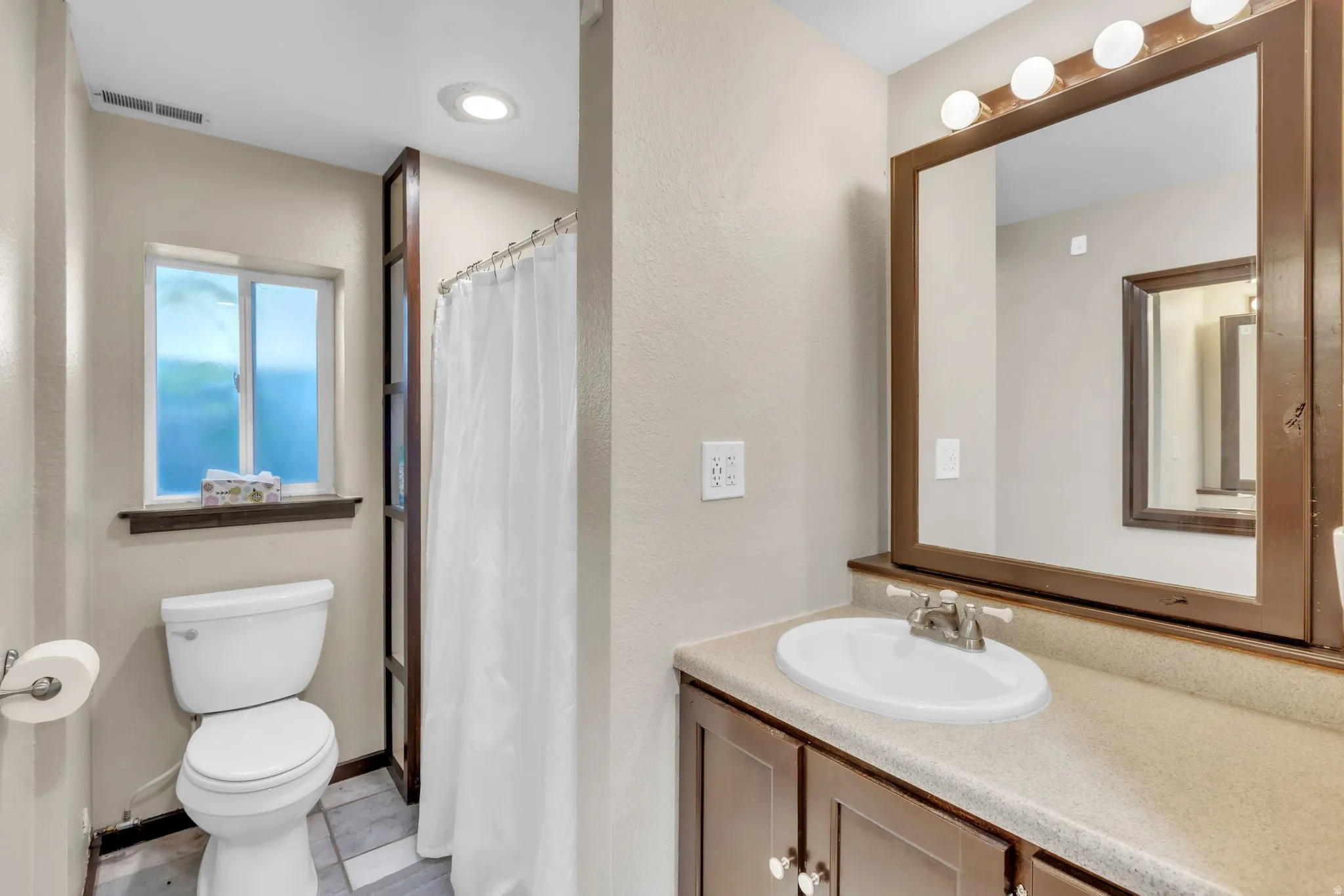 Full bathroom with curtained shower, vanity, and a textured wall