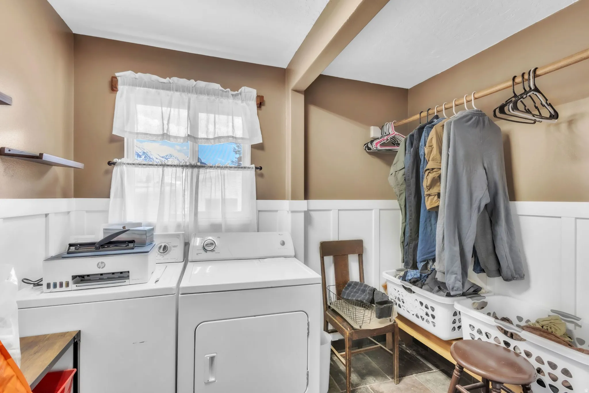 Laundry area featuring a wainscoted wall, separate washer and dryer, and a decorative wall