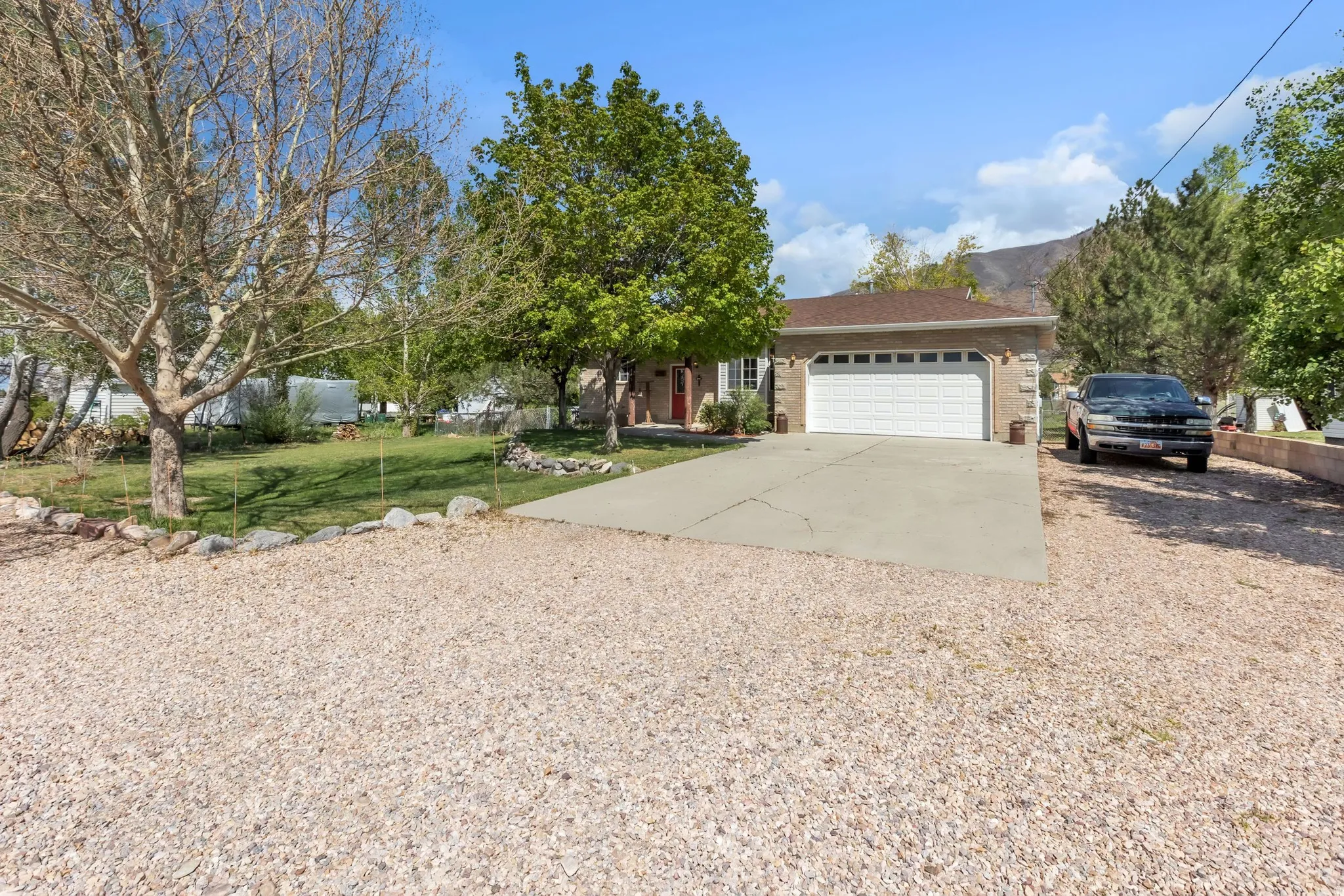 View of front facade with concrete driveway, a garage, a front lawn, brick siding, and covered porch