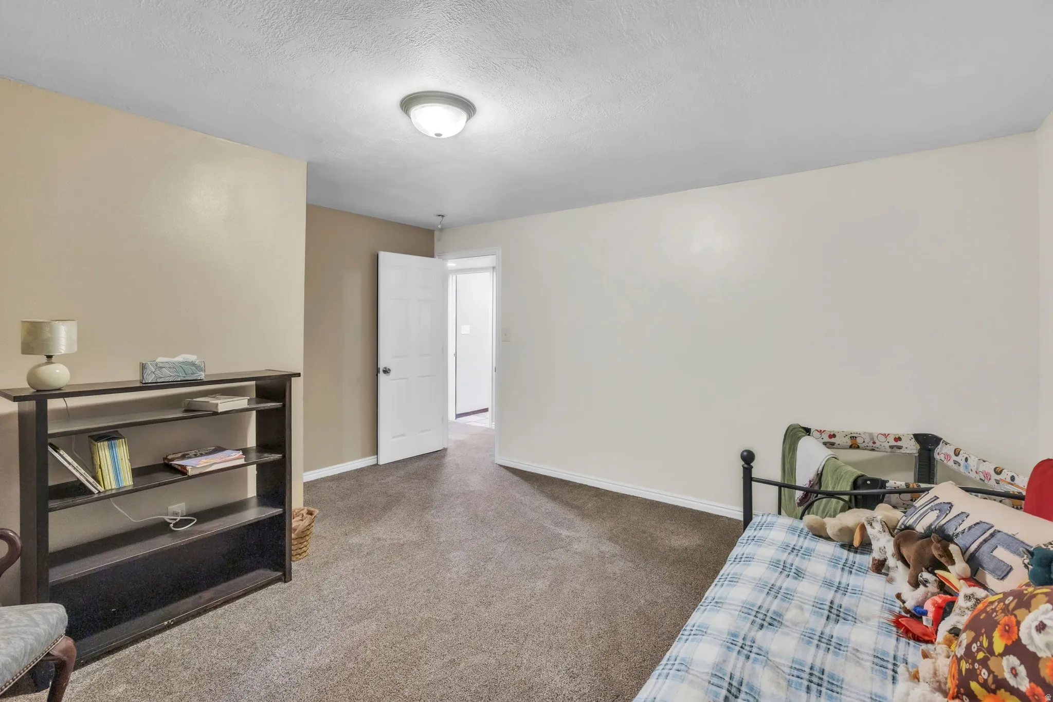 Bedroom with dark colored carpet and a textured ceiling