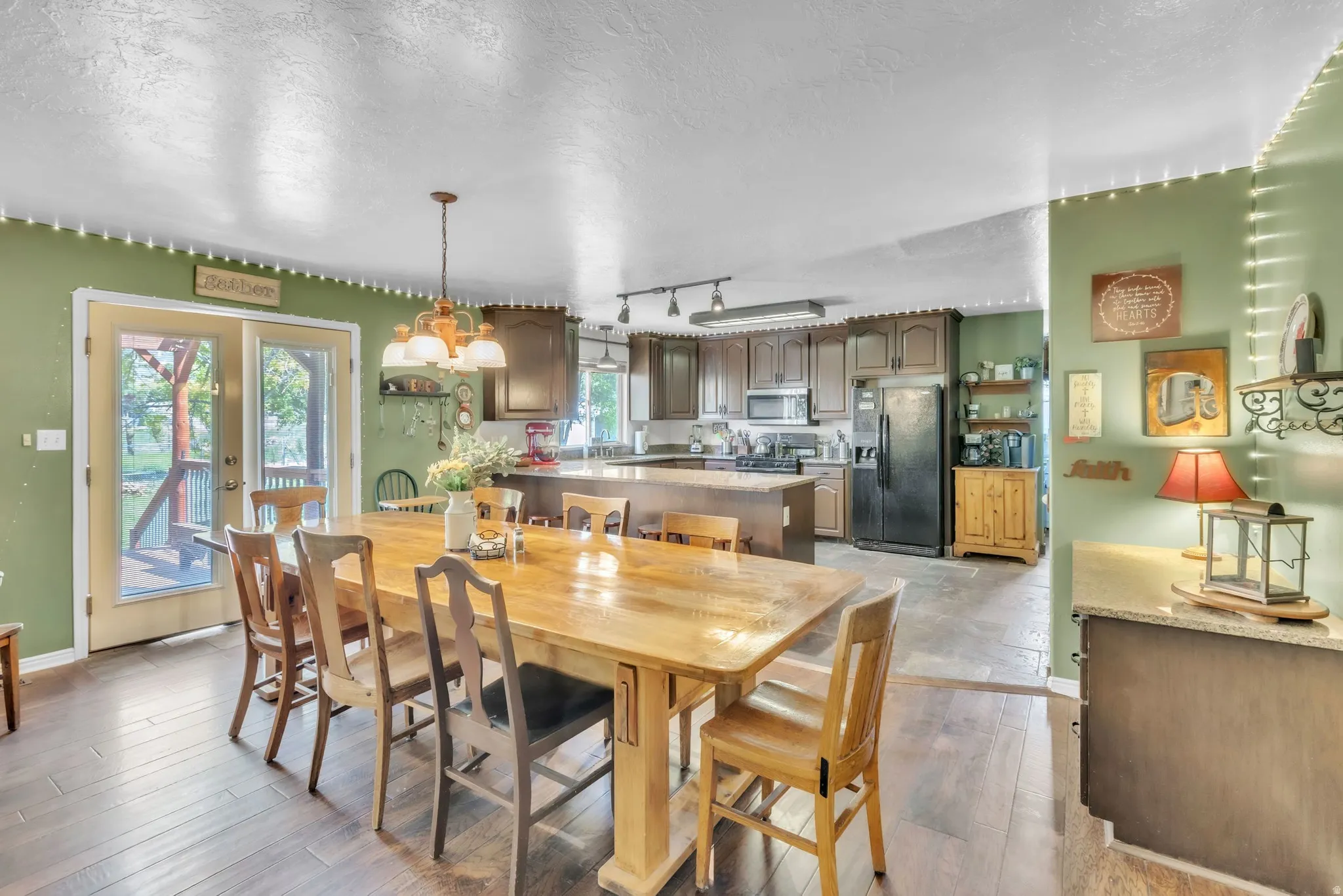 Dining space with a textured ceiling, rail lighting, and light wood-style floors
