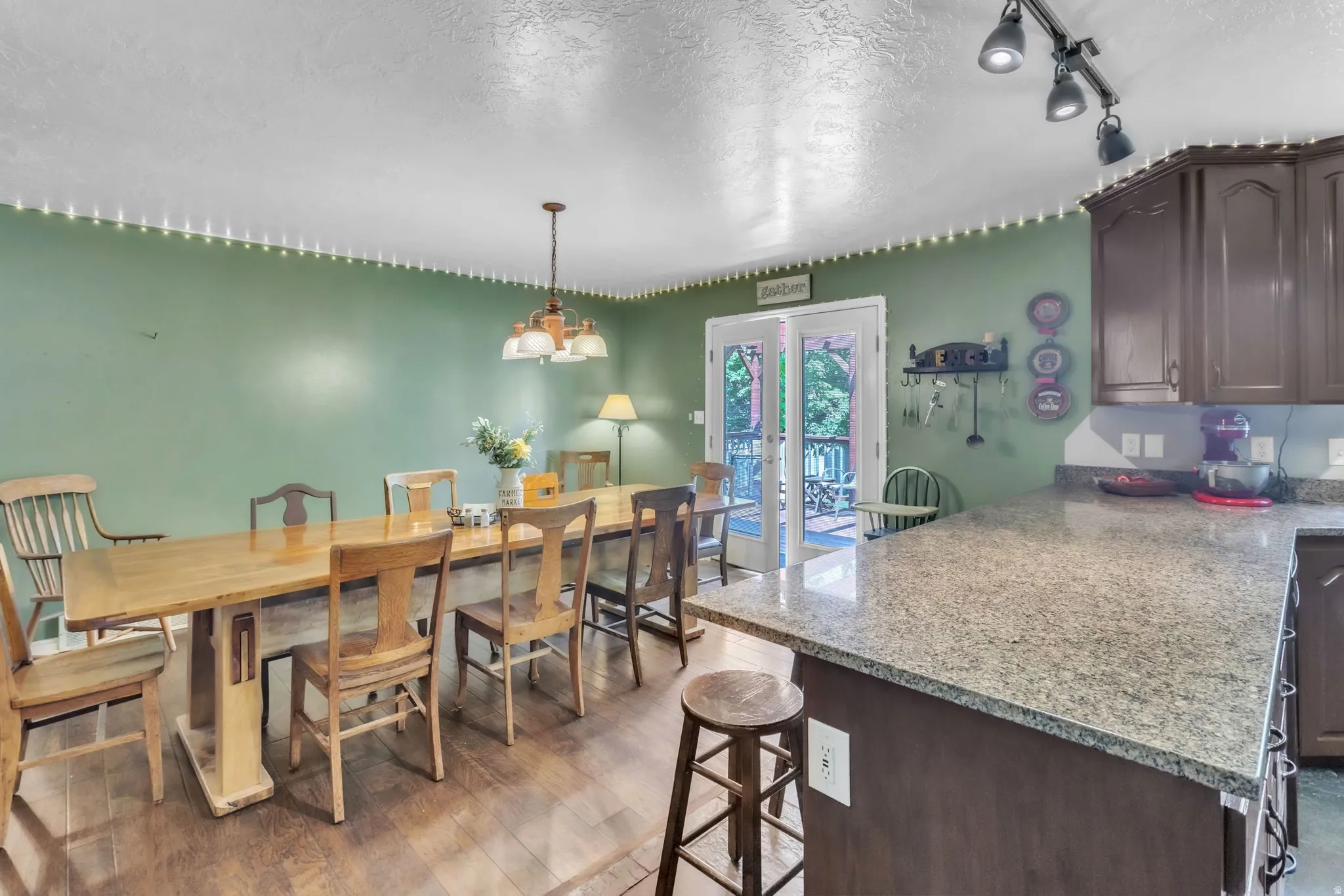 Dining space with a textured ceiling, dark wood-type flooring, french doors, and a chandelier