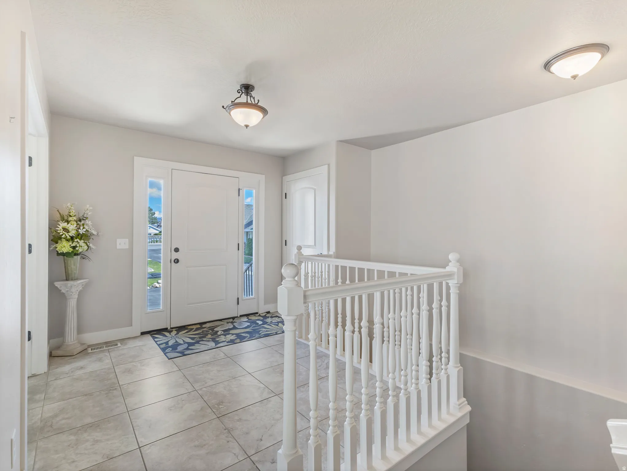 Entryway with light tile patterned flooring and baseboards