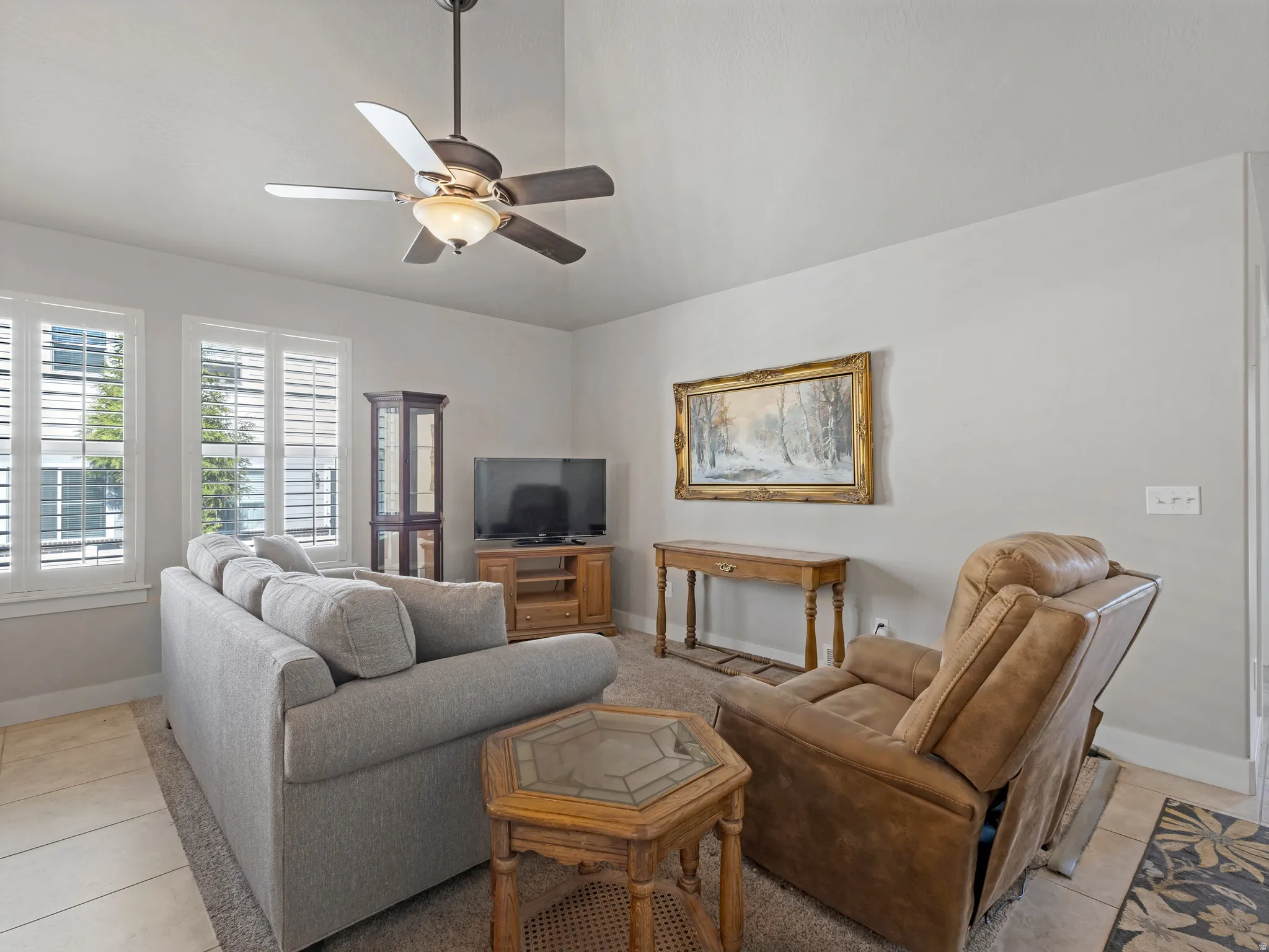 Living area featuring light tile patterned floors and ceiling fan