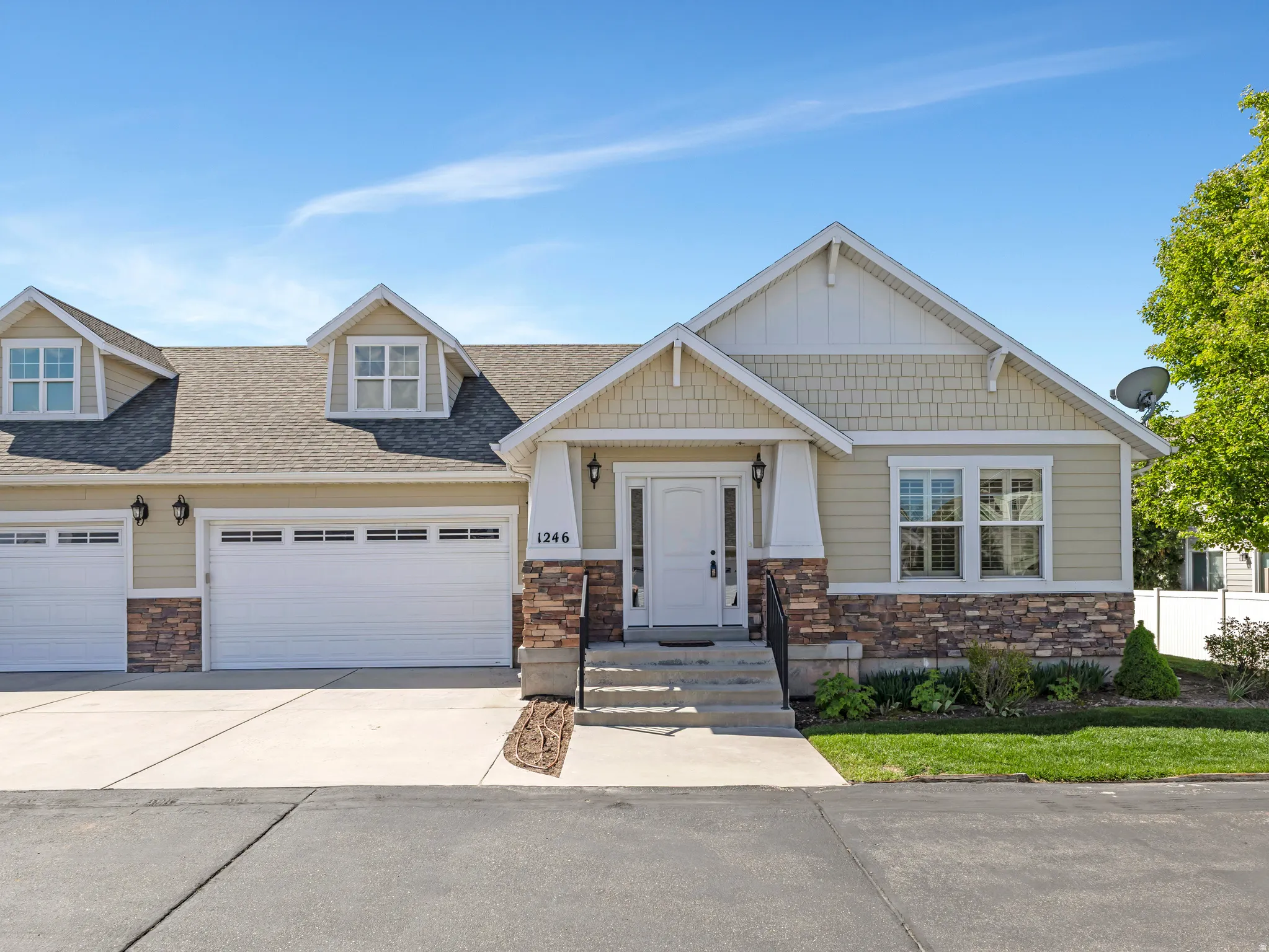 Craftsman-style home with stone siding, an attached garage, driveway, and roof with shingles