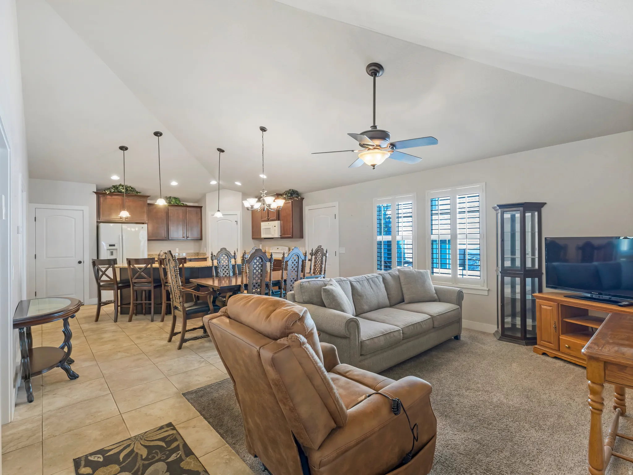 Living room with vaulted ceiling, hanging lights, a ceiling fan, and light tile patterned floors