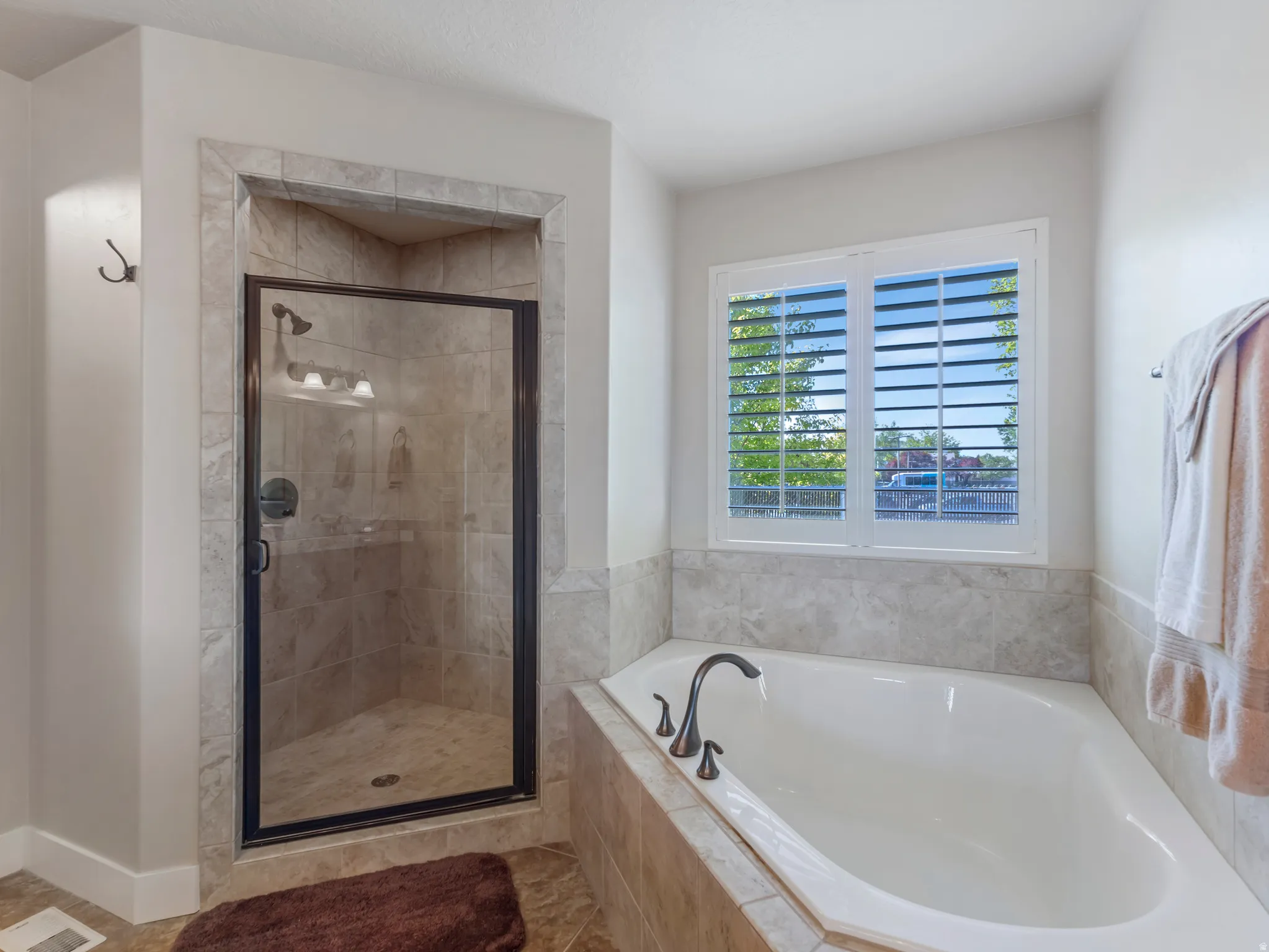 Full bath featuring a stall shower, a garden tub, and light tile patterned floors