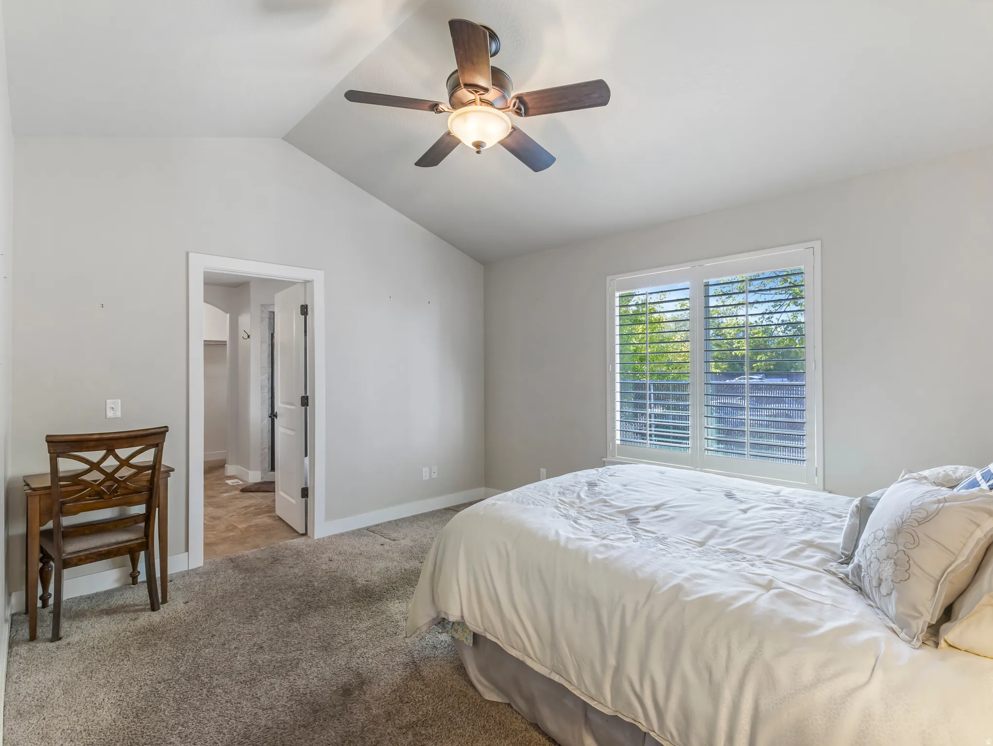 Bedroom featuring light colored carpet, a ceiling fan, and ensuite bathroom