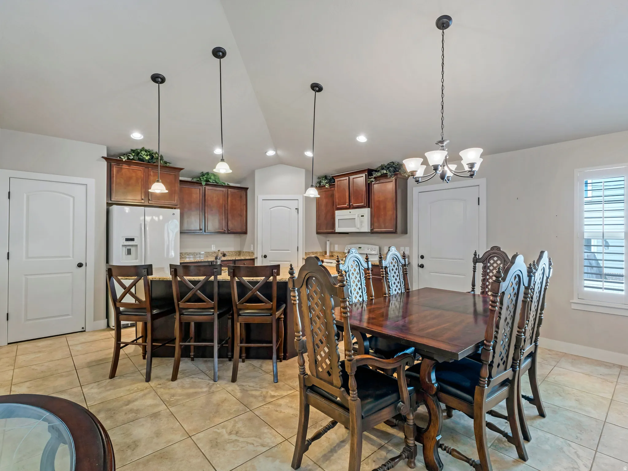 Dining room with lofted ceiling, hanging lights, and light tile patterned floors