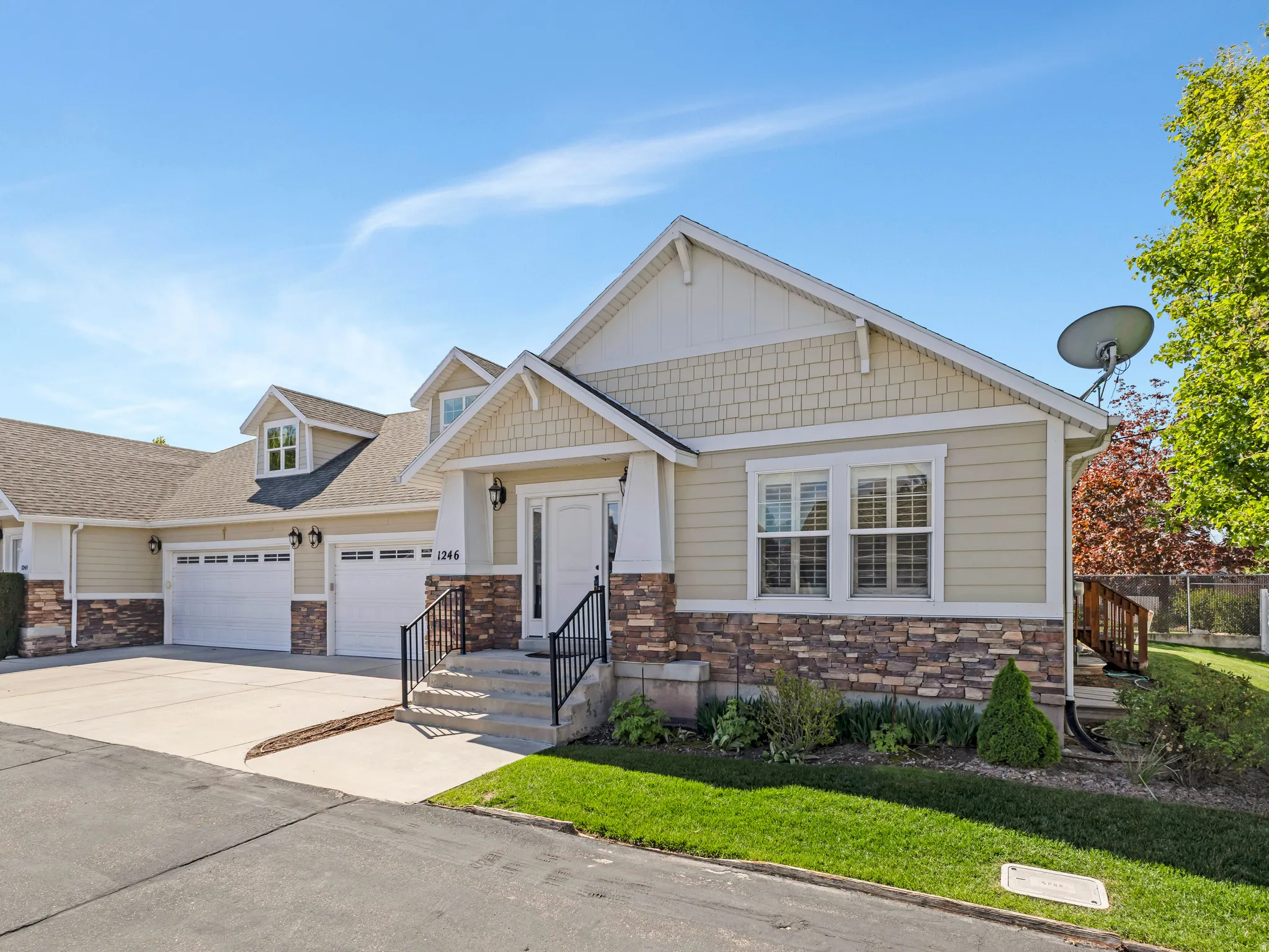 Craftsman inspired home featuring stone siding, an attached garage, and driveway
