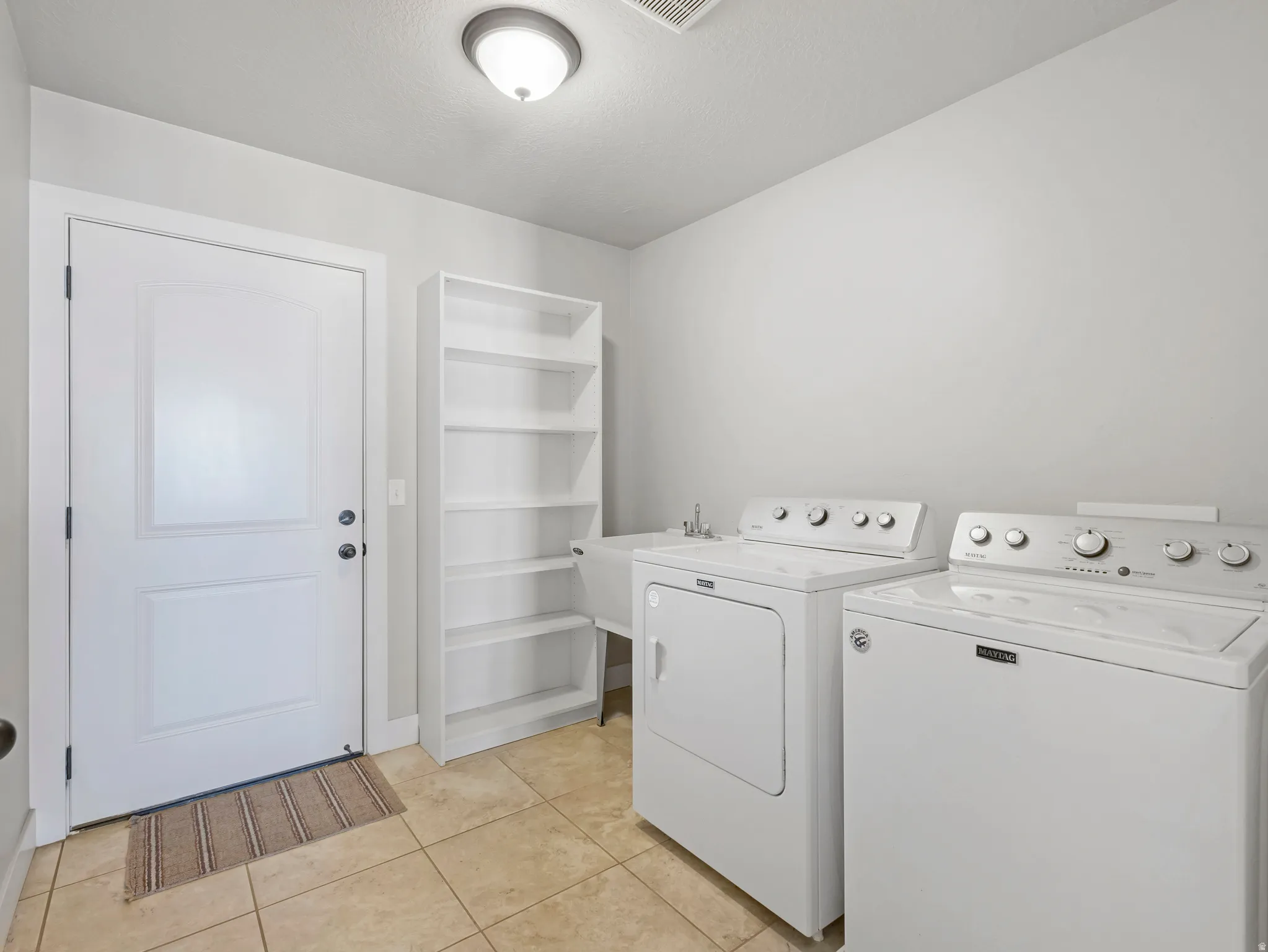 Laundry area featuring washer and clothes dryer and light tile patterned flooring
