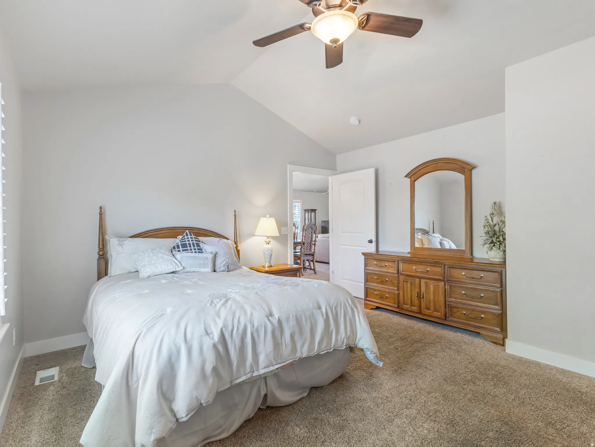 Carpeted bedroom featuring lofted ceiling and a ceiling fan