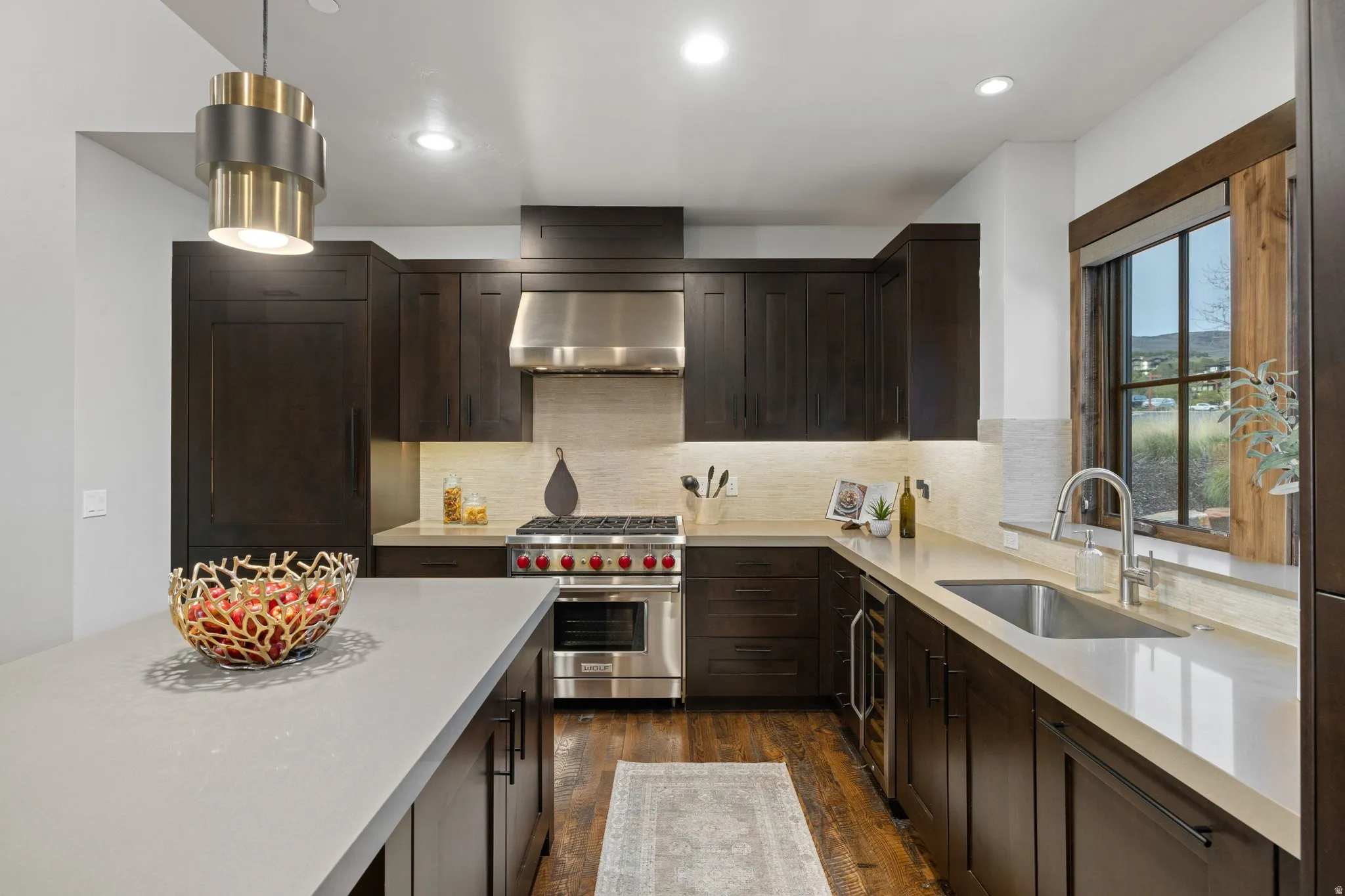 Kitchen featuring dark wood finish cabinets, premium stove, dark wood finished floors, light stone countertops, and backsplash