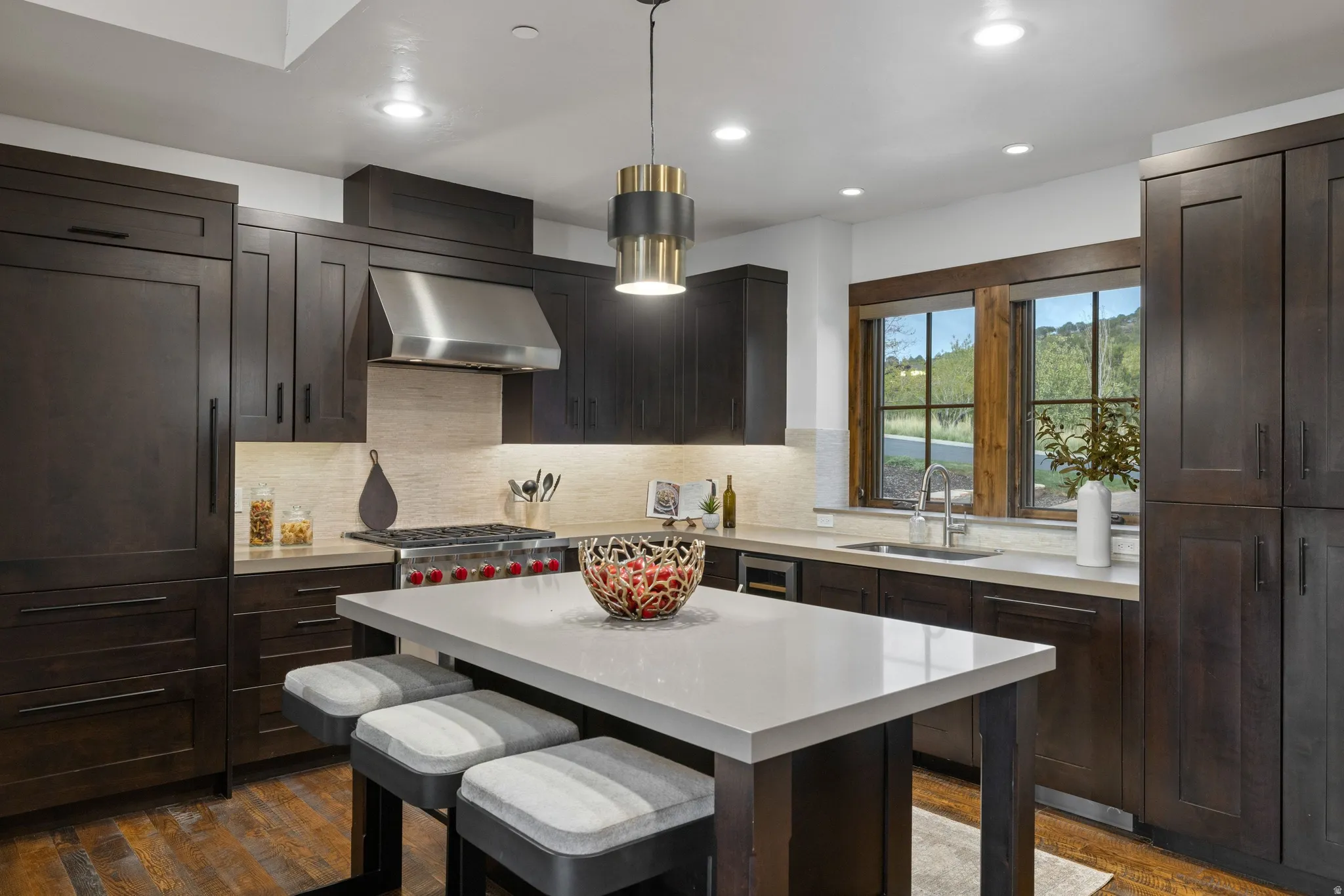 Kitchen with a kitchen breakfast bar, dark wood finish cabinets, range hood, dark wood finished floors, and a center island