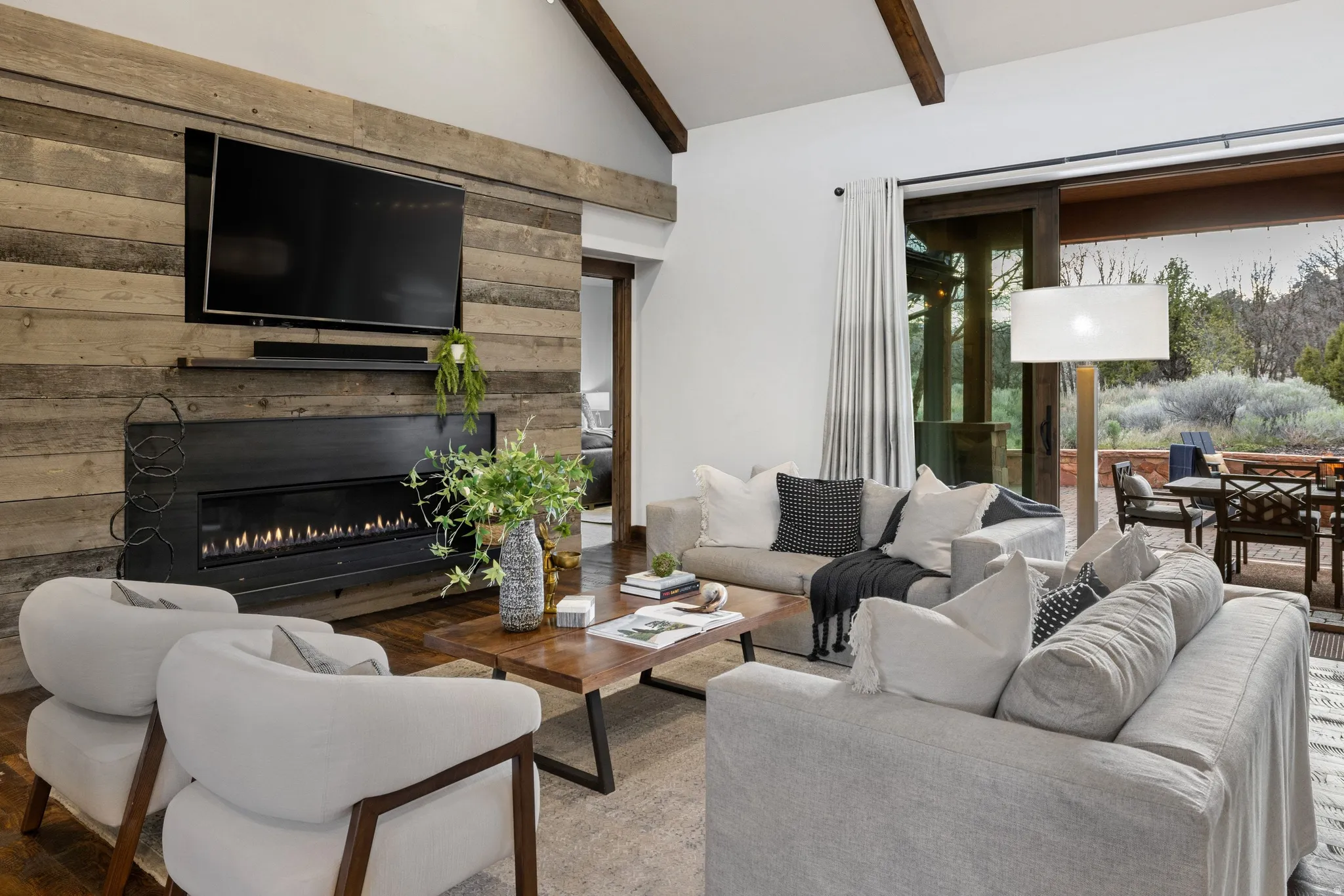 Living room featuring vaulted ceiling, a glass covered fireplace, and wood walls