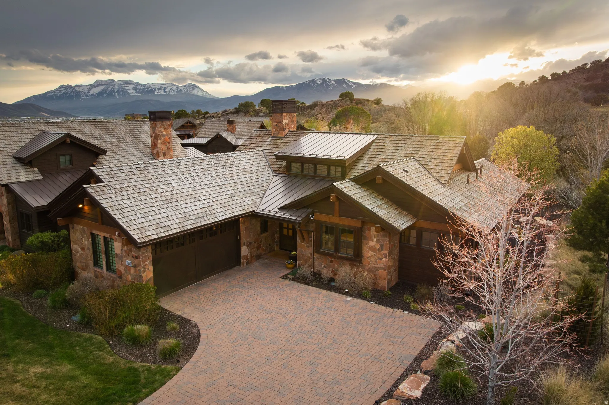 View of front of property featuring stone siding, a chimney, a garage, decorative driveway, and a mountain view