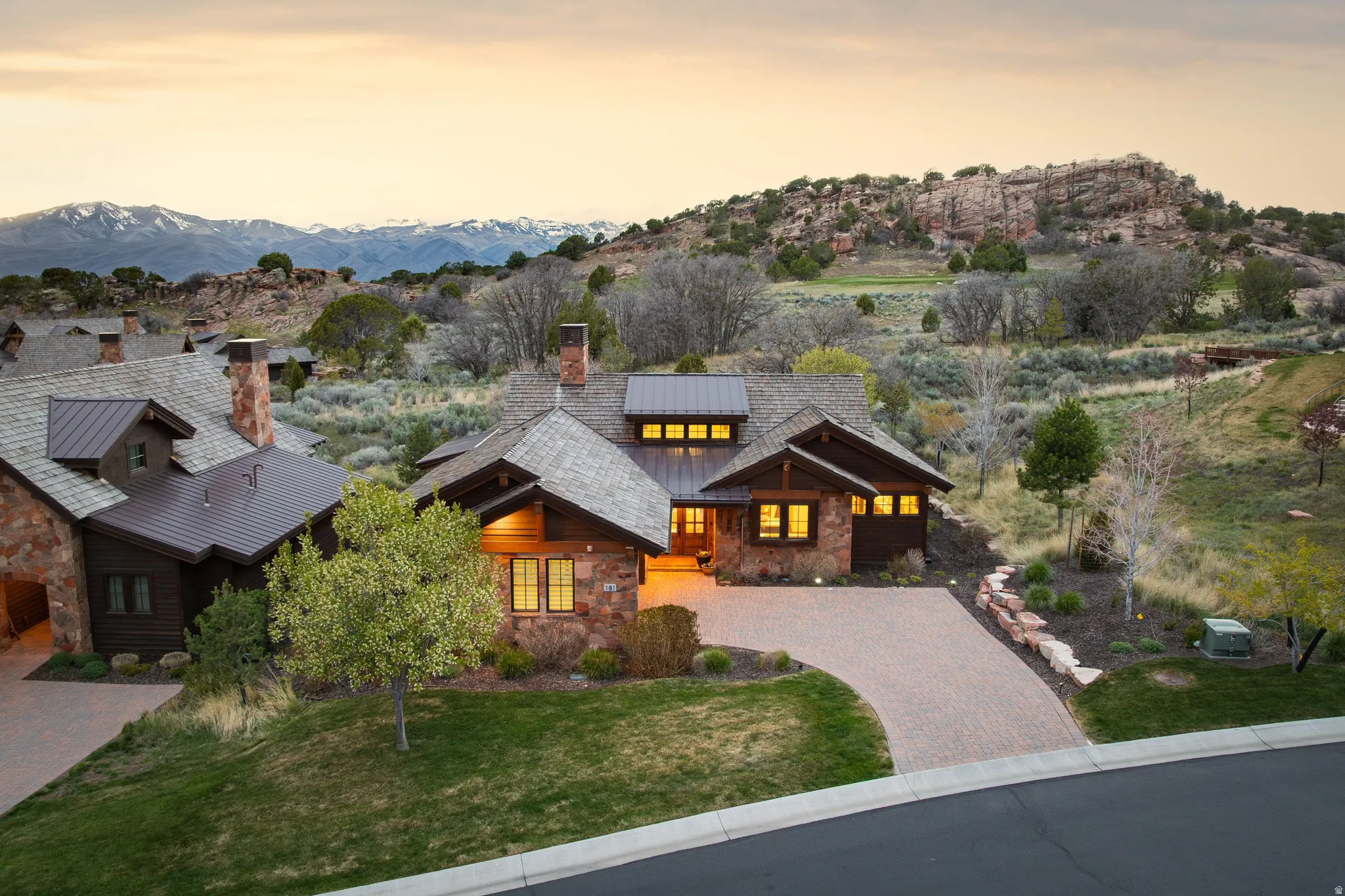 View of front of house featuring stone siding, a chimney, driveway, a porch, and a front lawn