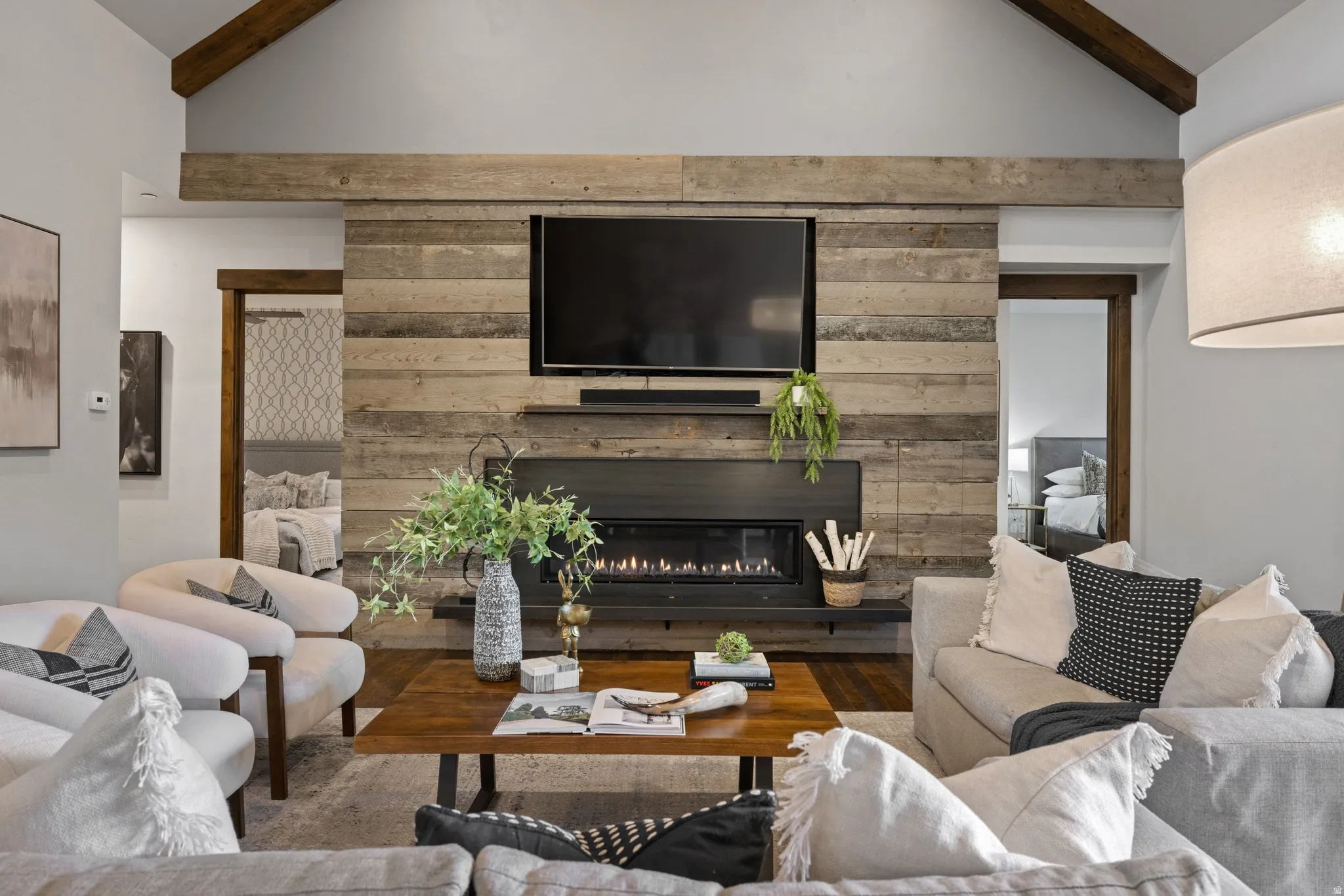 Living room featuring lofted ceiling with beams, a glass covered fireplace, and wood finished floors