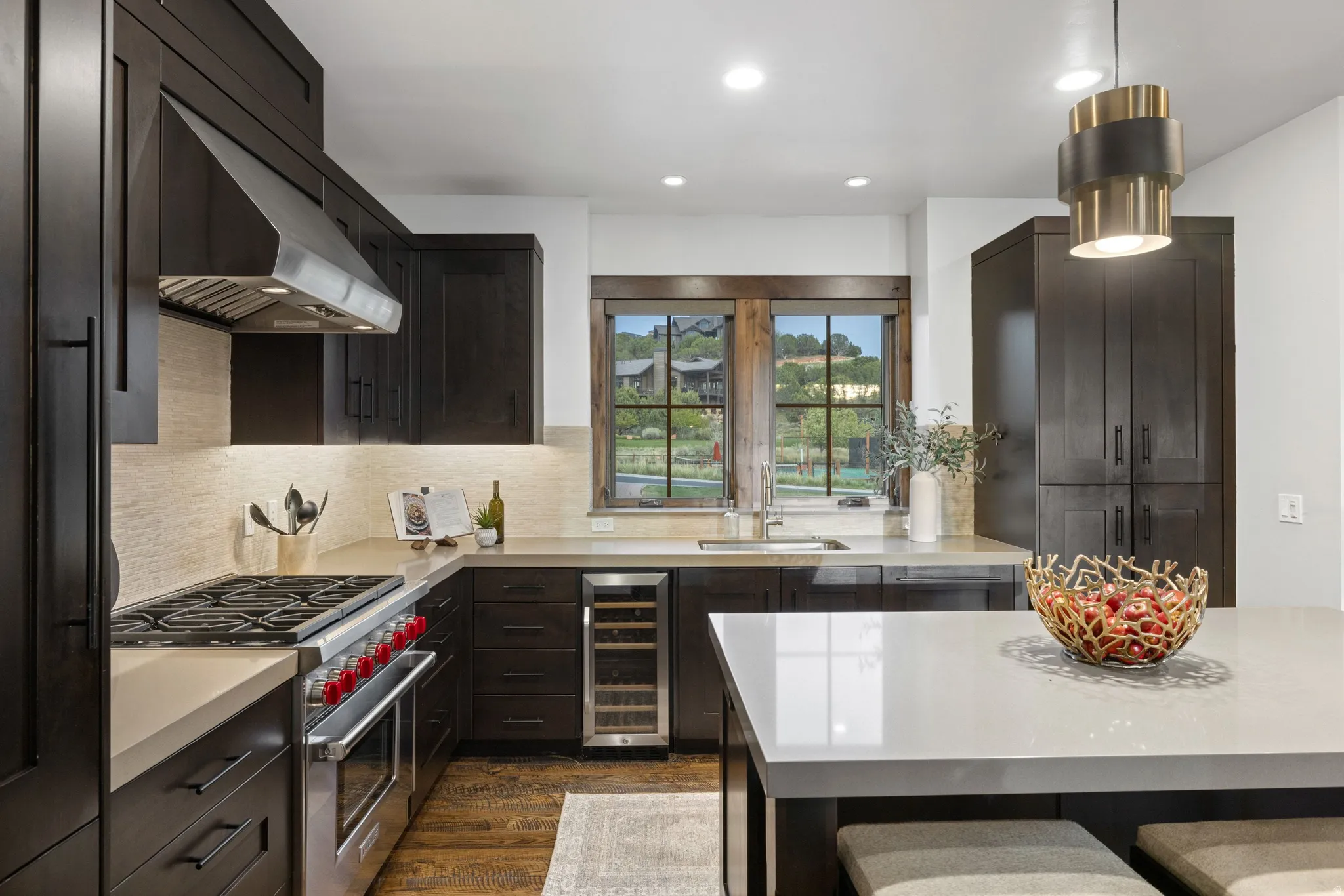 Kitchen featuring premium range, dark wood-style floors, dark wood finish cabinets, a breakfast bar, and recessed lighting