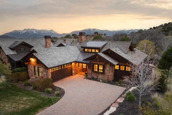 Chalet / cabin with stone siding, a chimney, a garage, decorative driveway, and a mountain view