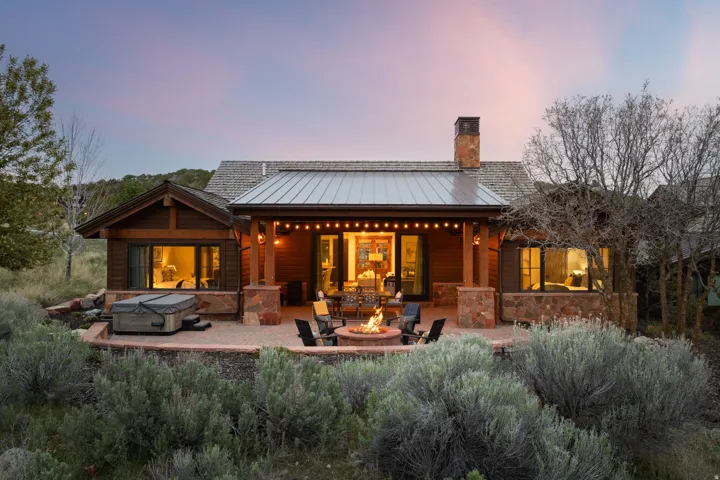 Back of house featuring a fire pit, a standing seam roof, a patio, a chimney, and a hot tub