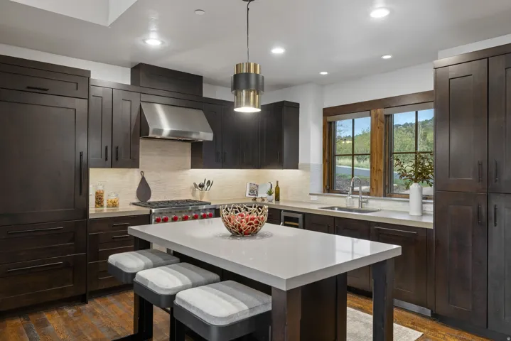 Kitchen with a kitchen breakfast bar, dark wood finish cabinets, range hood, dark wood finished floors, and a center island