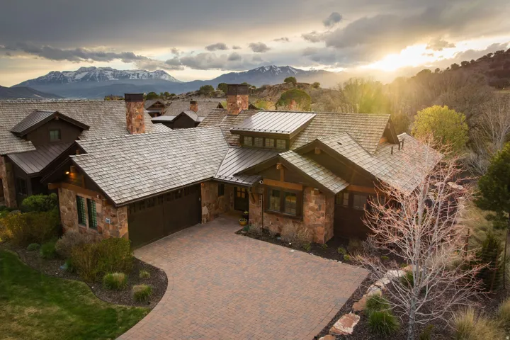 View of front of property featuring stone siding, a chimney, a garage, decorative driveway, and a mountain view