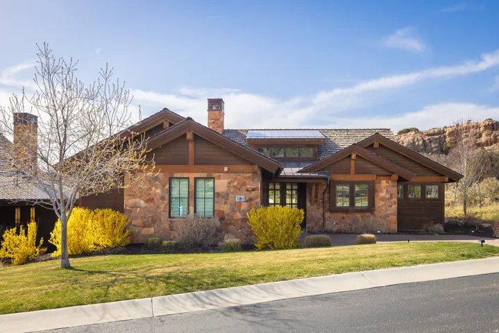 View of front of home featuring stone siding, a chimney, a front yard, and a standing seam roof