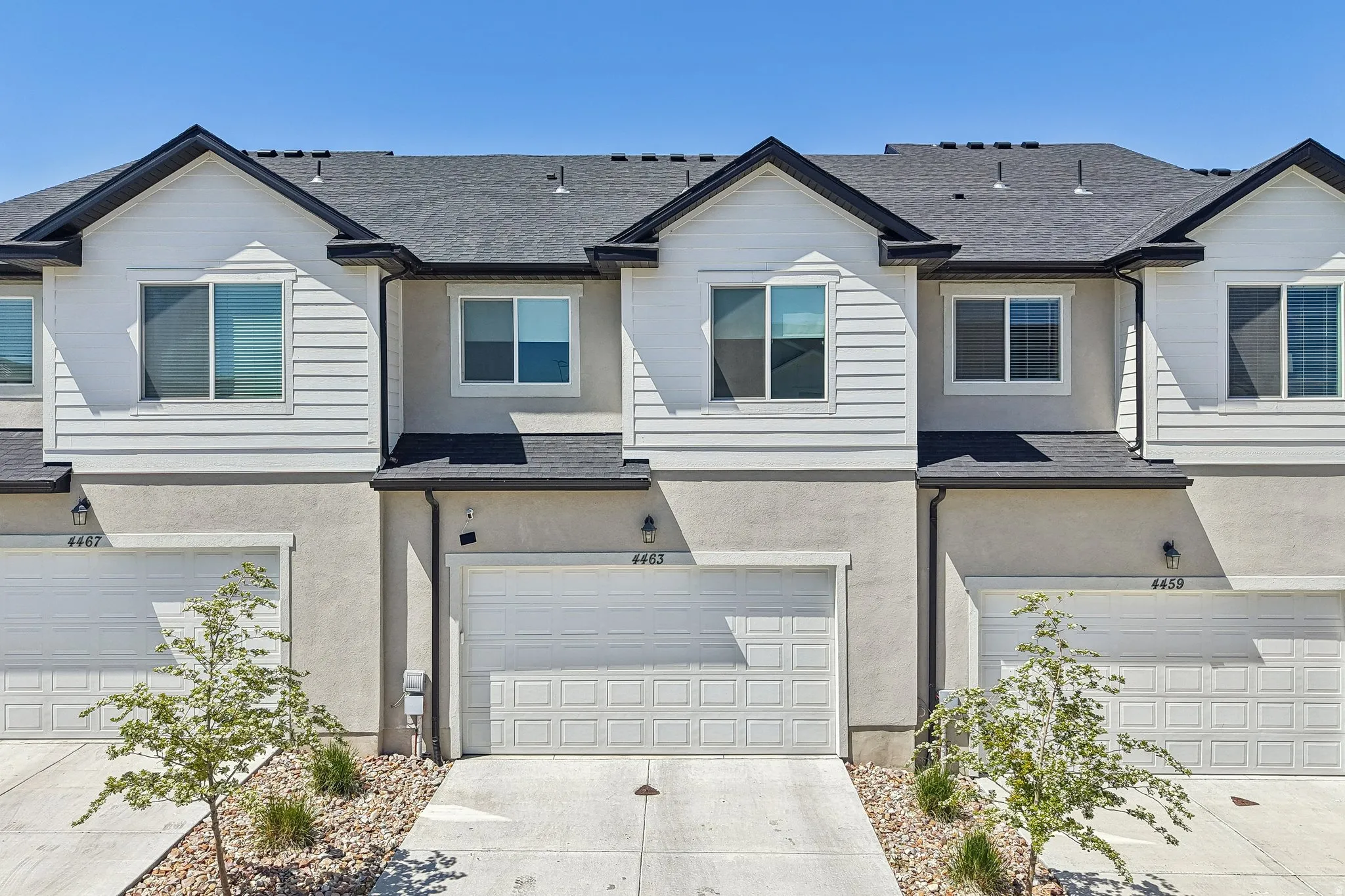 Traditional home featuring stucco siding, a shingled roof, and driveway
