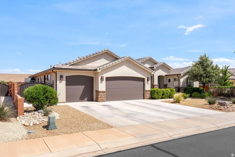 Ranch-style house with an attached garage, stucco siding, concrete driveway, stone siding, and a tile roof