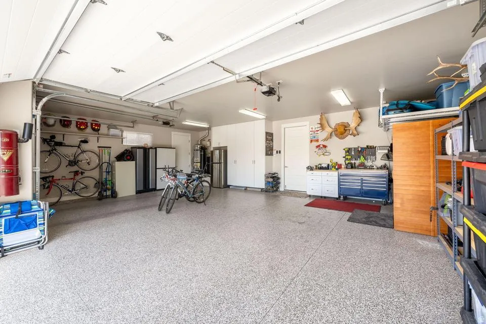 Garage featuring freestanding refrigerator and secured water heater