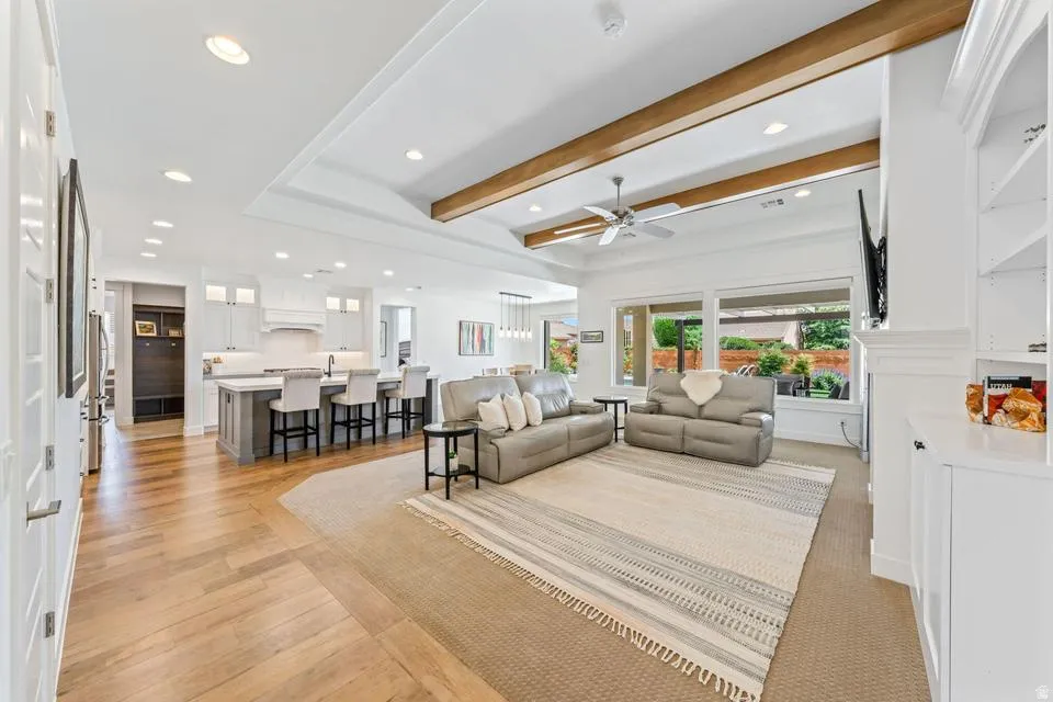 Living area with recessed lighting, beamed ceiling, a ceiling fan, and light wood-style flooring