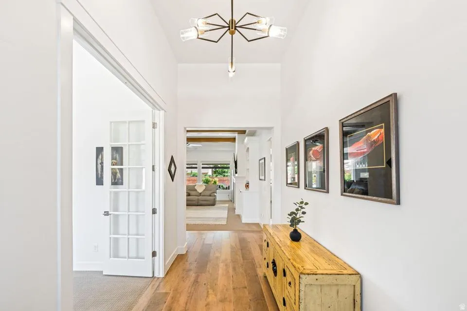 Hall with light wood-style flooring and suspended lighting