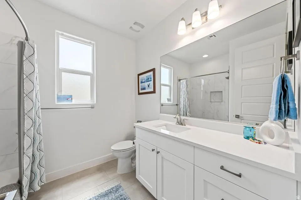 Full bath with vanity, curtained shower, and light tile patterned flooring