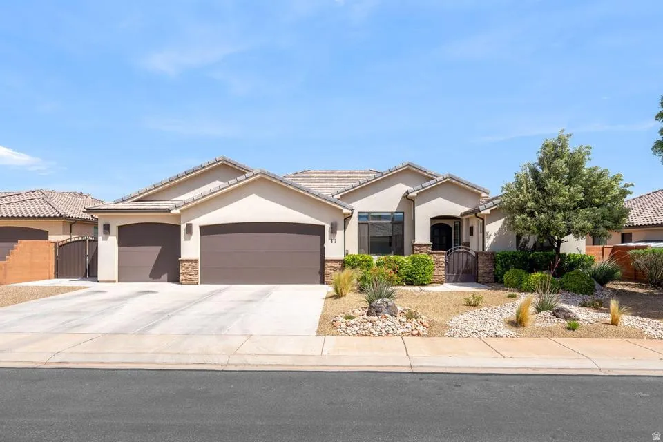 Ranch-style house featuring a gate, a garage, stone siding, and stucco siding