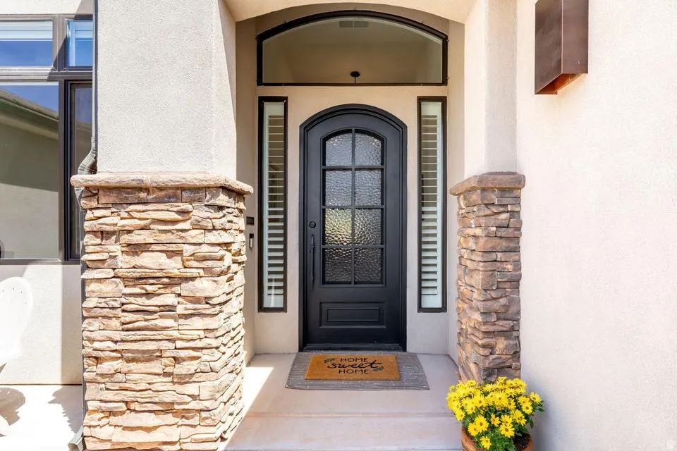 Doorway to property featuring stone siding and stucco siding