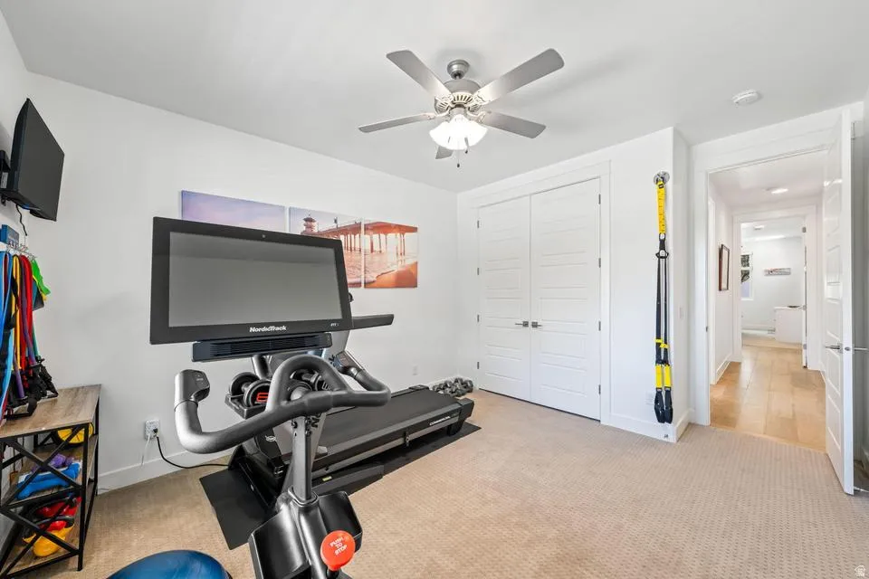 Exercise room with light carpet and a ceiling fan