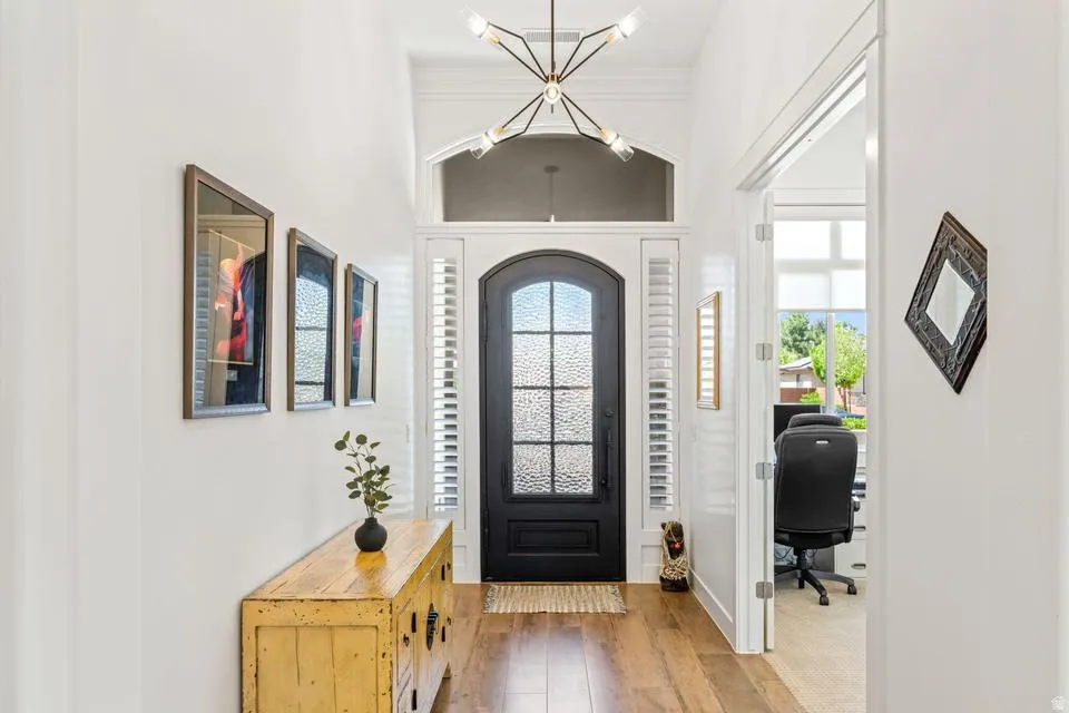Foyer entrance featuring light wood-style flooring, a chandelier, and ornamental molding