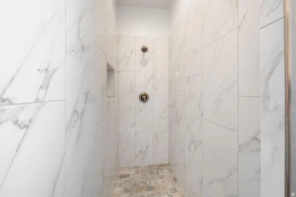 Full bath with a marble finish shower