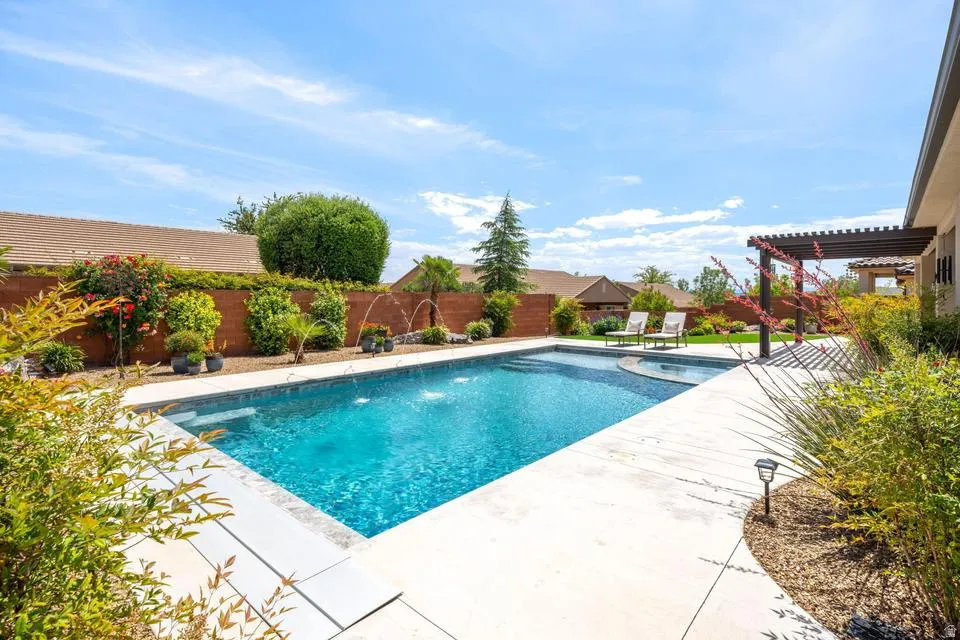 View of swimming pool with patio surround, a fenced backyard, and a pergola