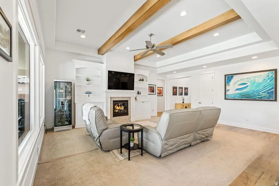 Living area featuring a premium fireplace, beam ceiling, ceiling fan, recessed lighting, and built in shelves